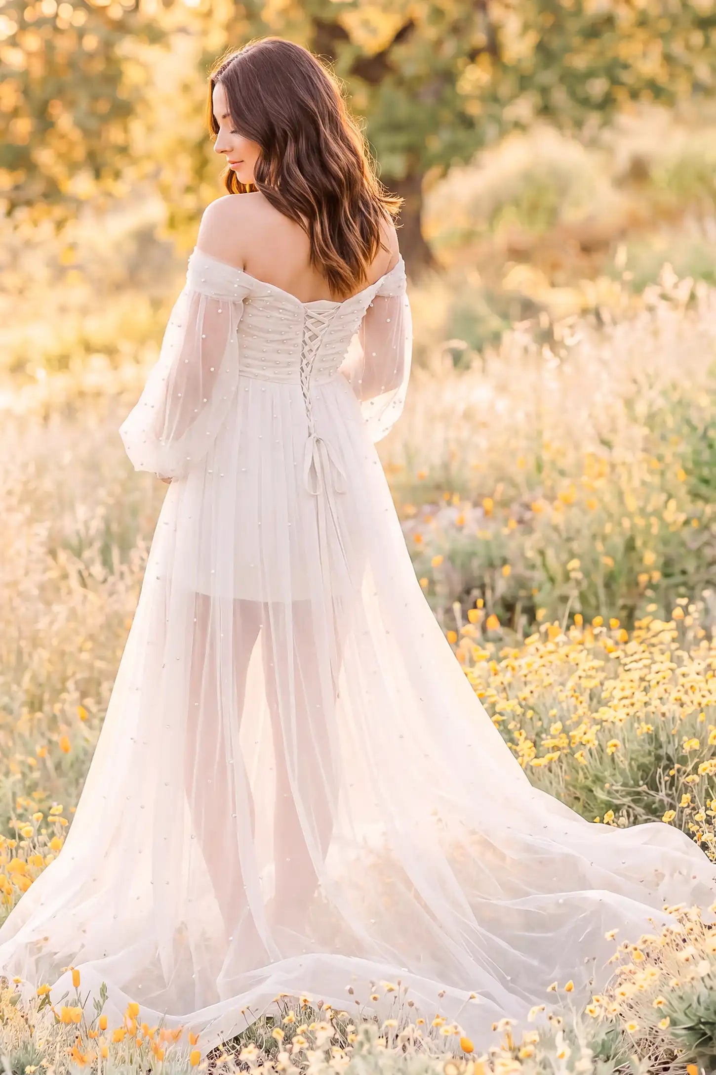 Off-Shoulder Empire Waist Tulle Maternity Gown Off-Shoulder Empire Waist Maternity Gown in Ivory showcasing flowing tulle movement, outdoor lifestyle back view on a pregnant model.