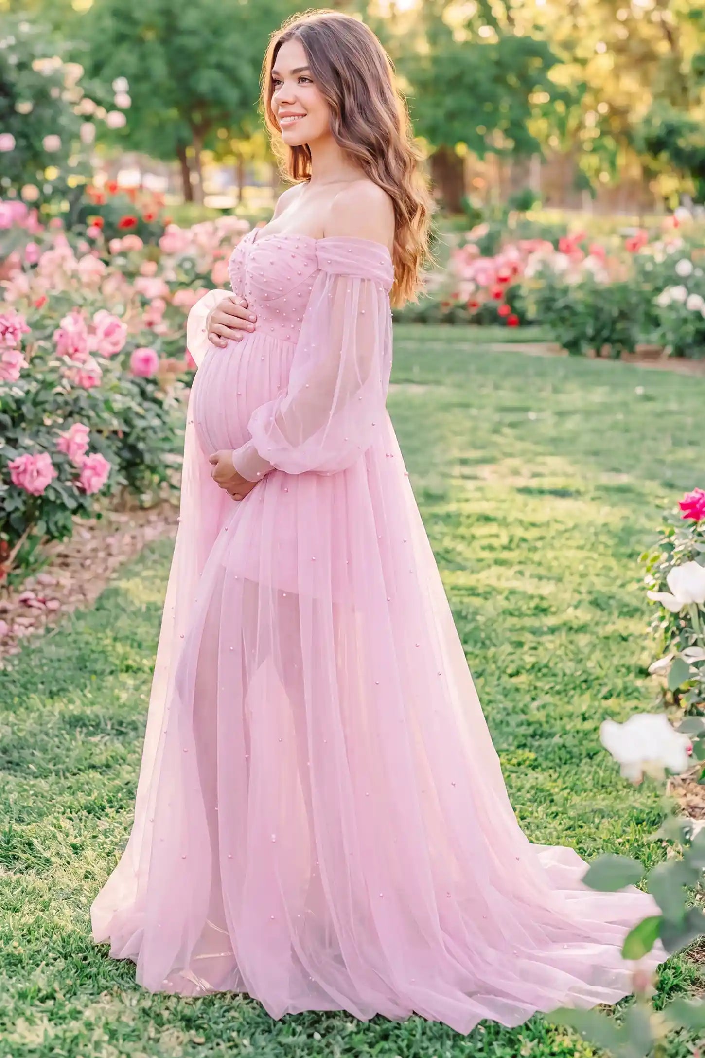Off-Shoulder Empire Waist Tulle Maternity Gown Off-Shoulder Empire Waist Maternity Gown in Pink highlighting the empire waist, outdoor lifestyle side view on a pregnant model.