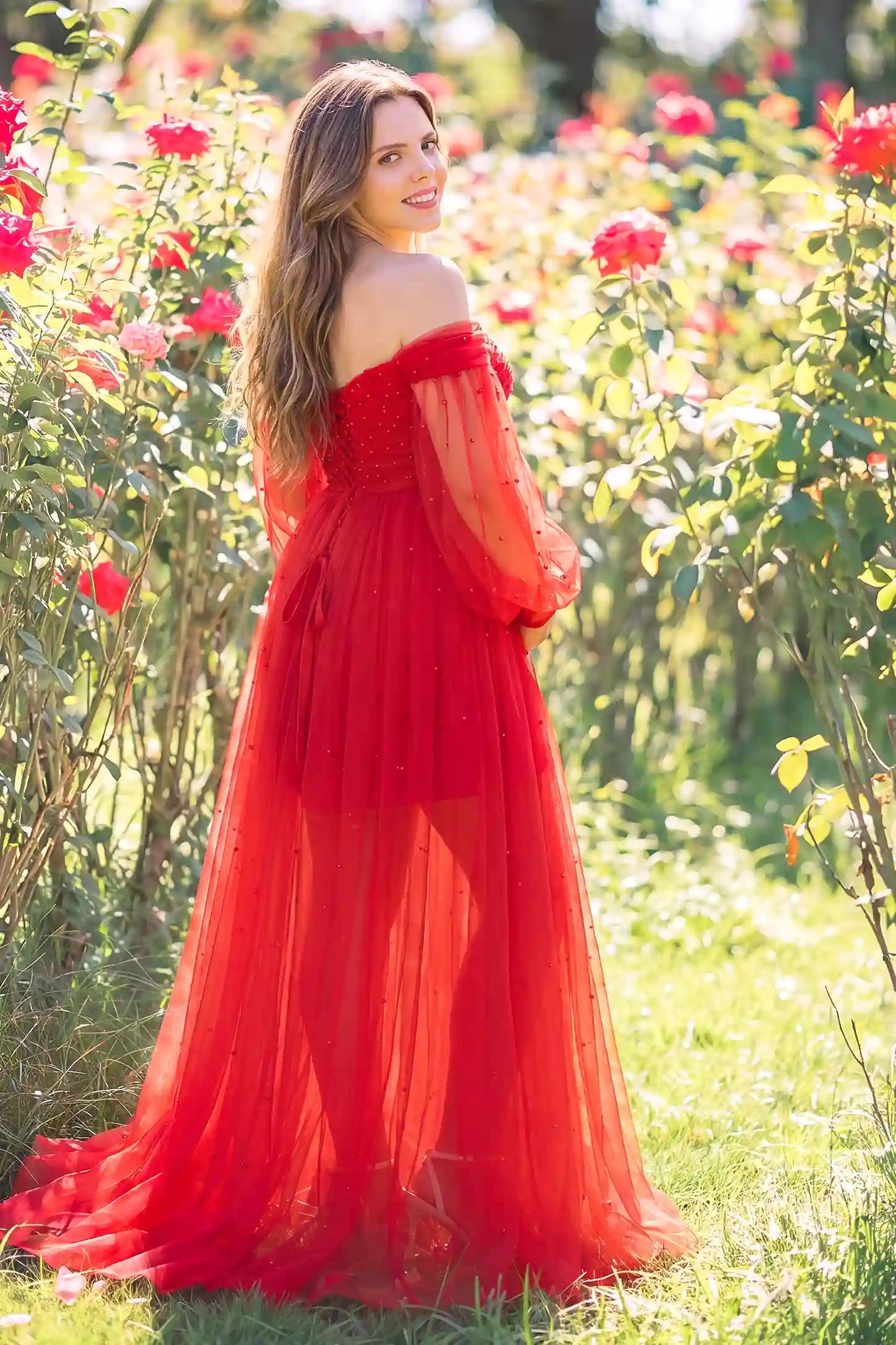 Off-Shoulder Empire Waist Tulle Maternity Gown Off-Shoulder Empire Waist Maternity Gown in Red showcasing flowing tulle movement, outdoor lifestyle back view on a pregnant model.