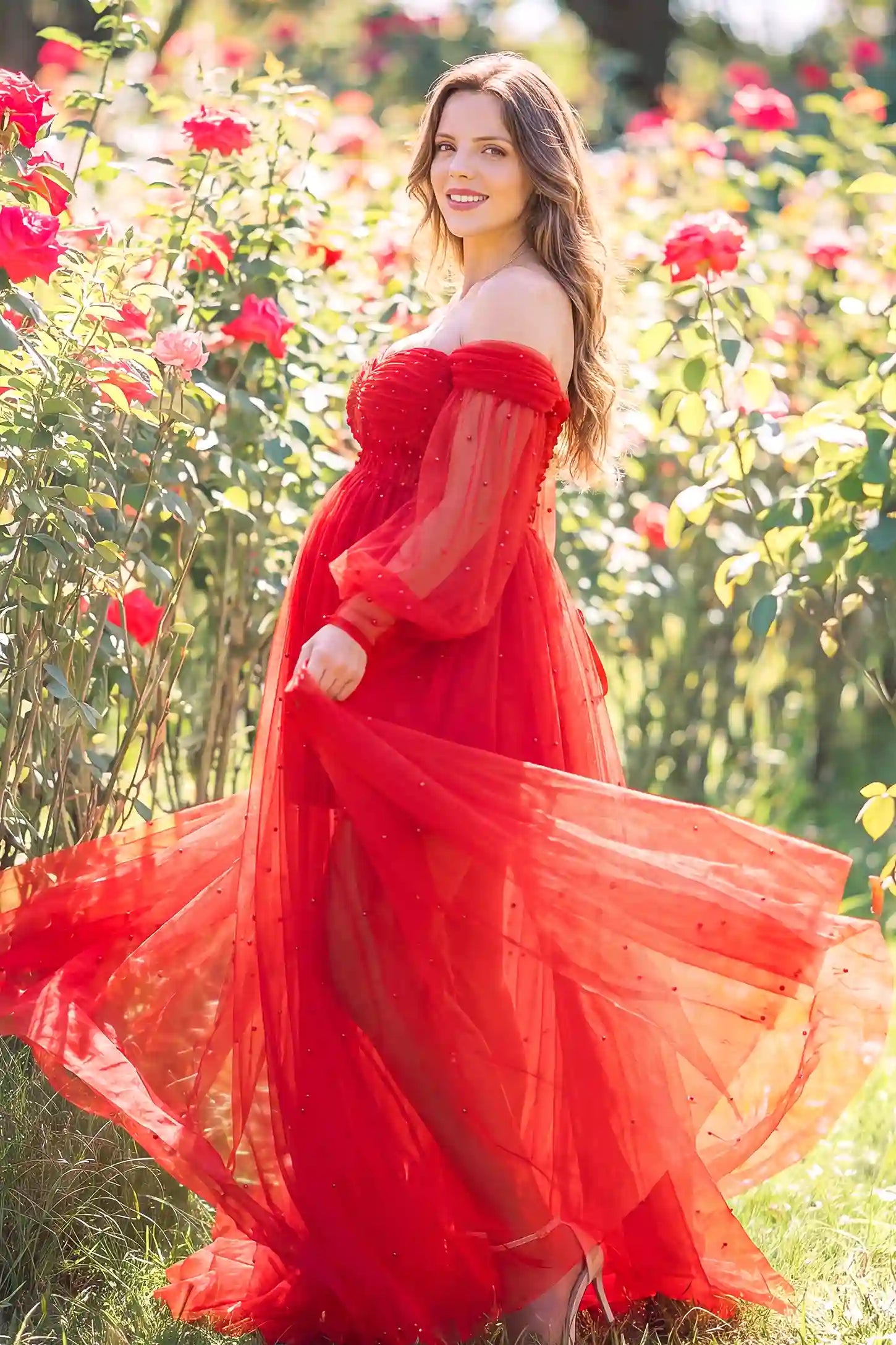 Off-Shoulder Empire Waist Tulle Maternity Gown Off-Shoulder Empire Waist Maternity Gown in Red highlighting the empire waist, outdoor lifestyle side view on a pregnant model.