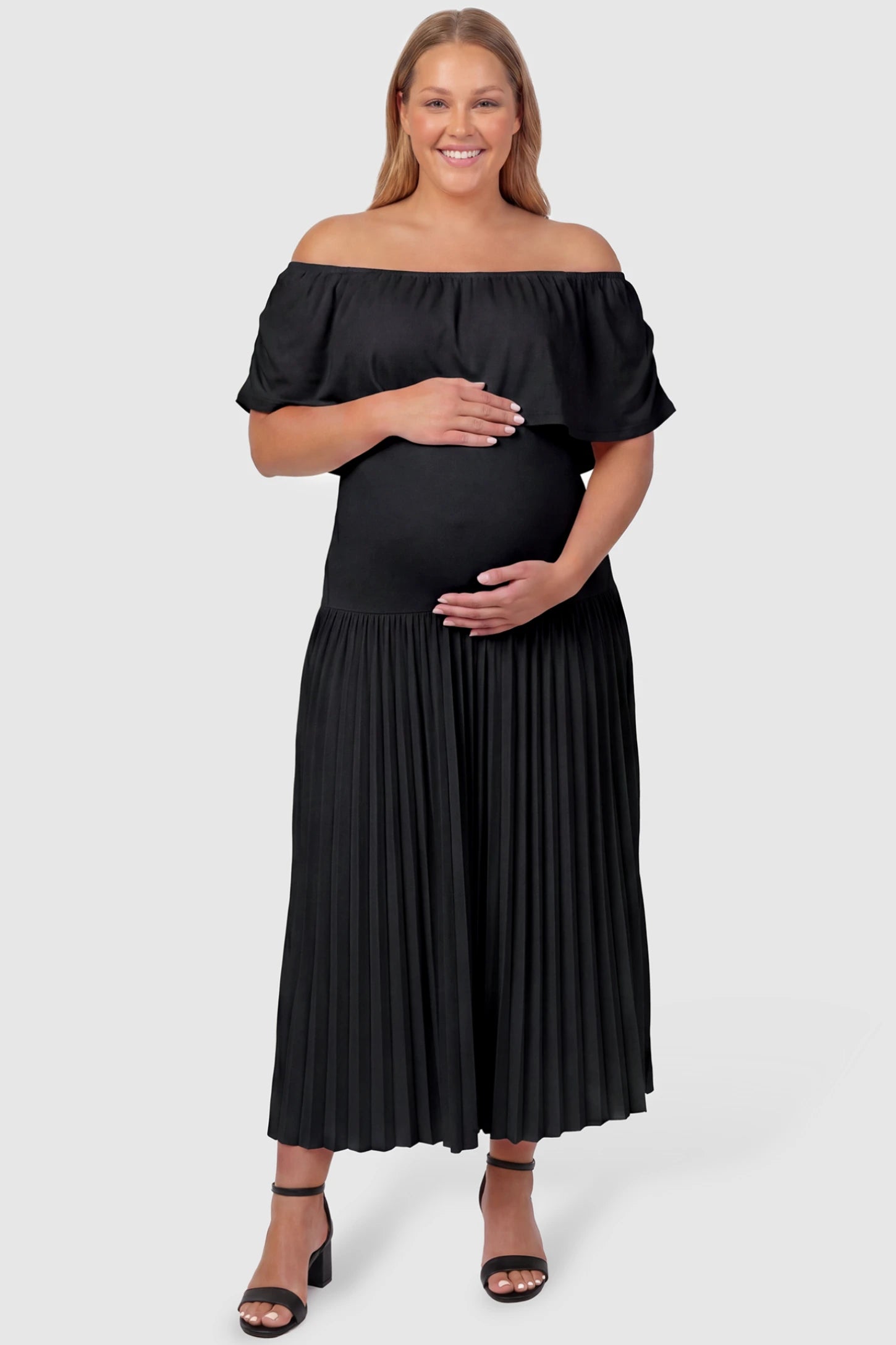 Pleated Off Shoulder Maternity Maxi Dress Pleated Off Shoulder Maternity Maxi Dress  in Black featuring a high stretch pleated maxi skirt on a plus size pregnant model, front view.