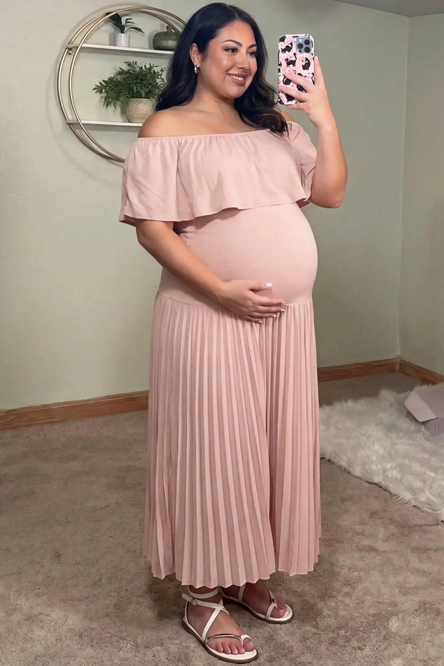 Pleated Off Shoulder Maternity Maxi Dress Pleated Off Shoulder Maternity Maxi Dress in Pink featuring a high stretch pleated maxi skirt on a pregnant model during an indoor setting, side view.