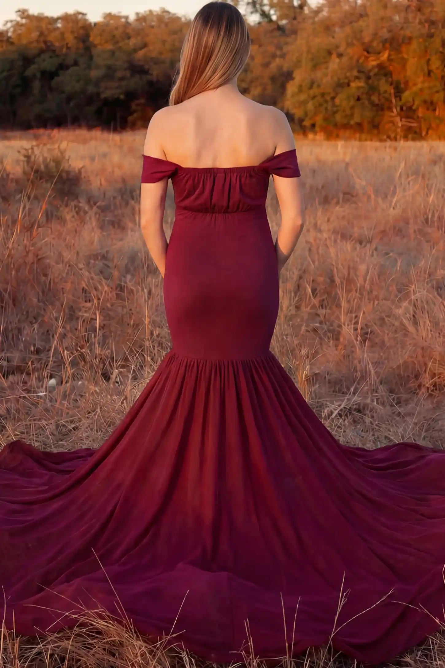 Solid Off Shoulder Mermaid Maternity Photoshoot Gown Solid Off Shoulder Mermaid Maternity Photoshoot Gown in burgundy featuring dramatic pleated train on a pregnant model showing back.