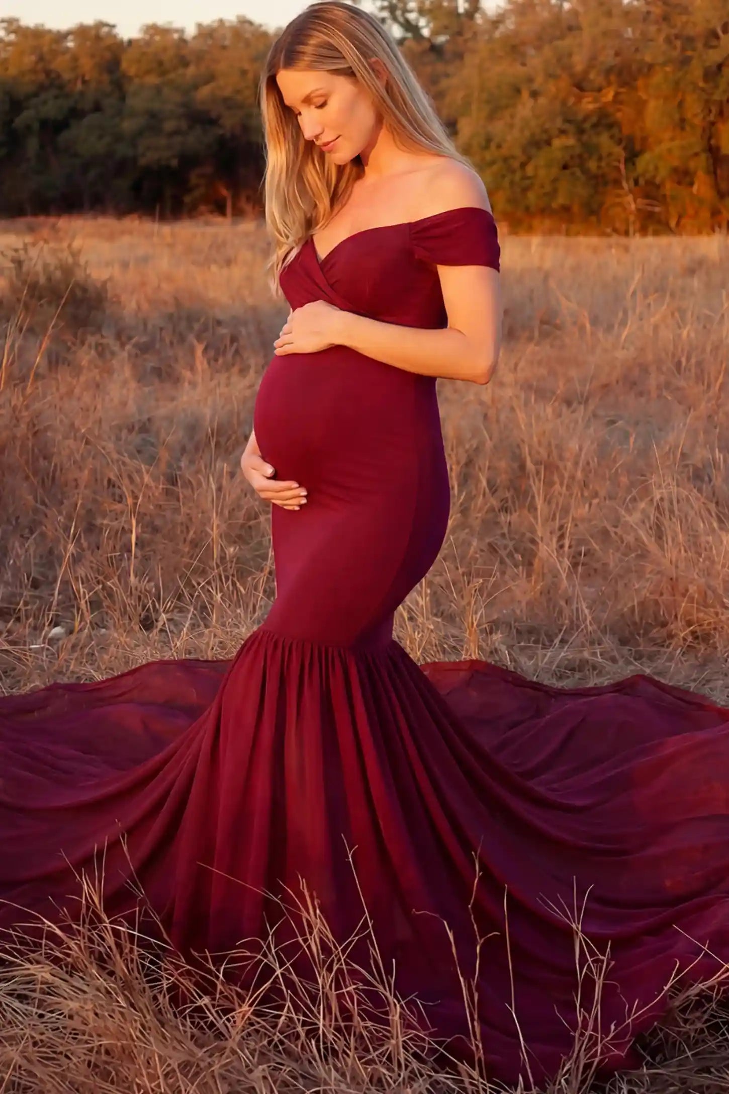 Solid Off Shoulder Mermaid Maternity Photoshoot Gown Solid Off Shoulder Mermaid Maternity Photoshoot Gown in burgundy featuring a sweetheart neckline and dramatic pleated train on a pregnant model showing front.