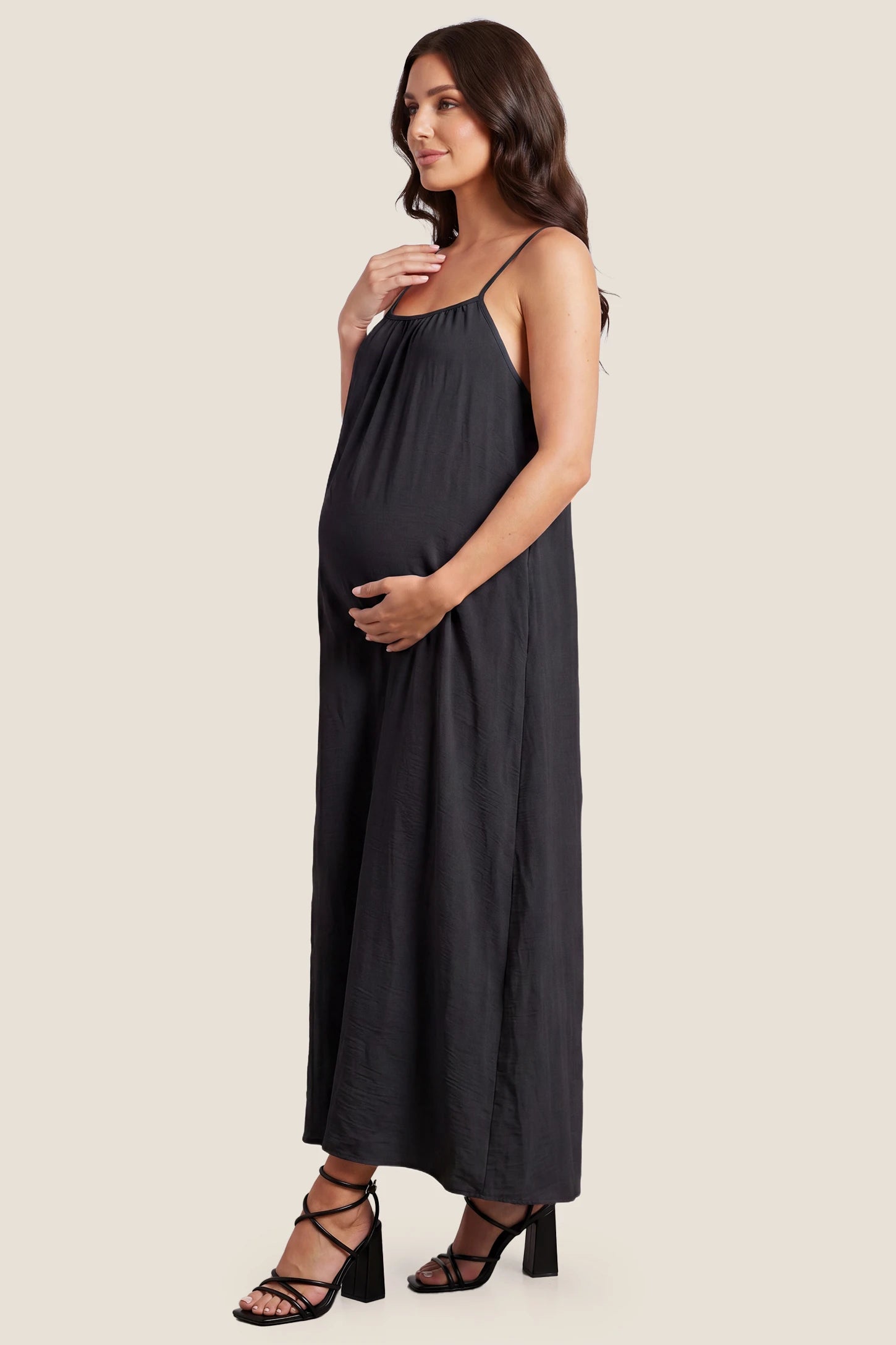 Open Back Flowy Cami Maternity Dress Open Back Flowy Cami Long Maternity Dress in Black with a flowy silhouette, side view on a pregnant model.