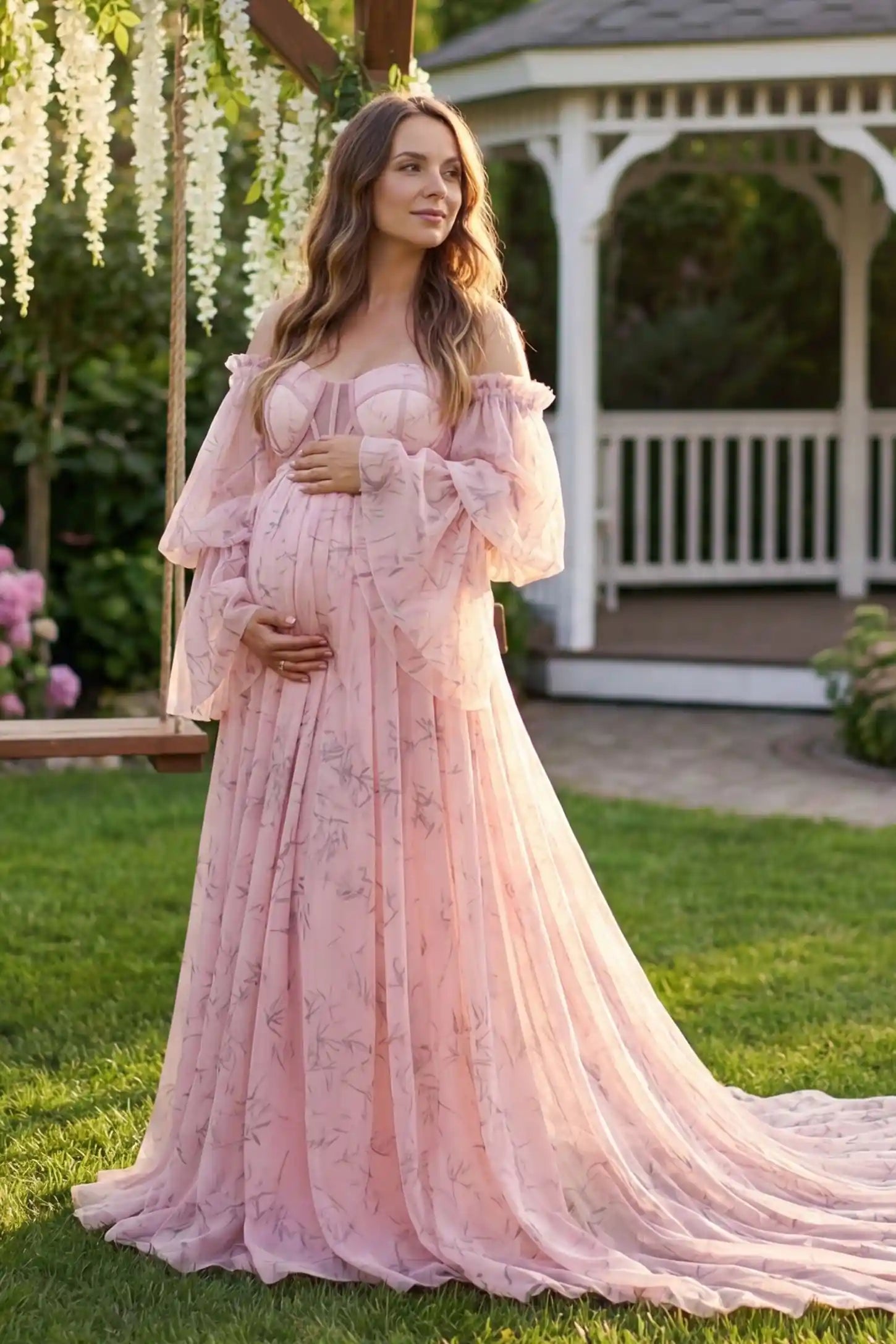 Organza Tie-Back Off-Shoulder Long Sleeve Maternity Gown Organza Tie-Back Off-Shoulder Maternity Gown in Pink featuring a flowy organza overlay on a pregnant model by a gazebo.