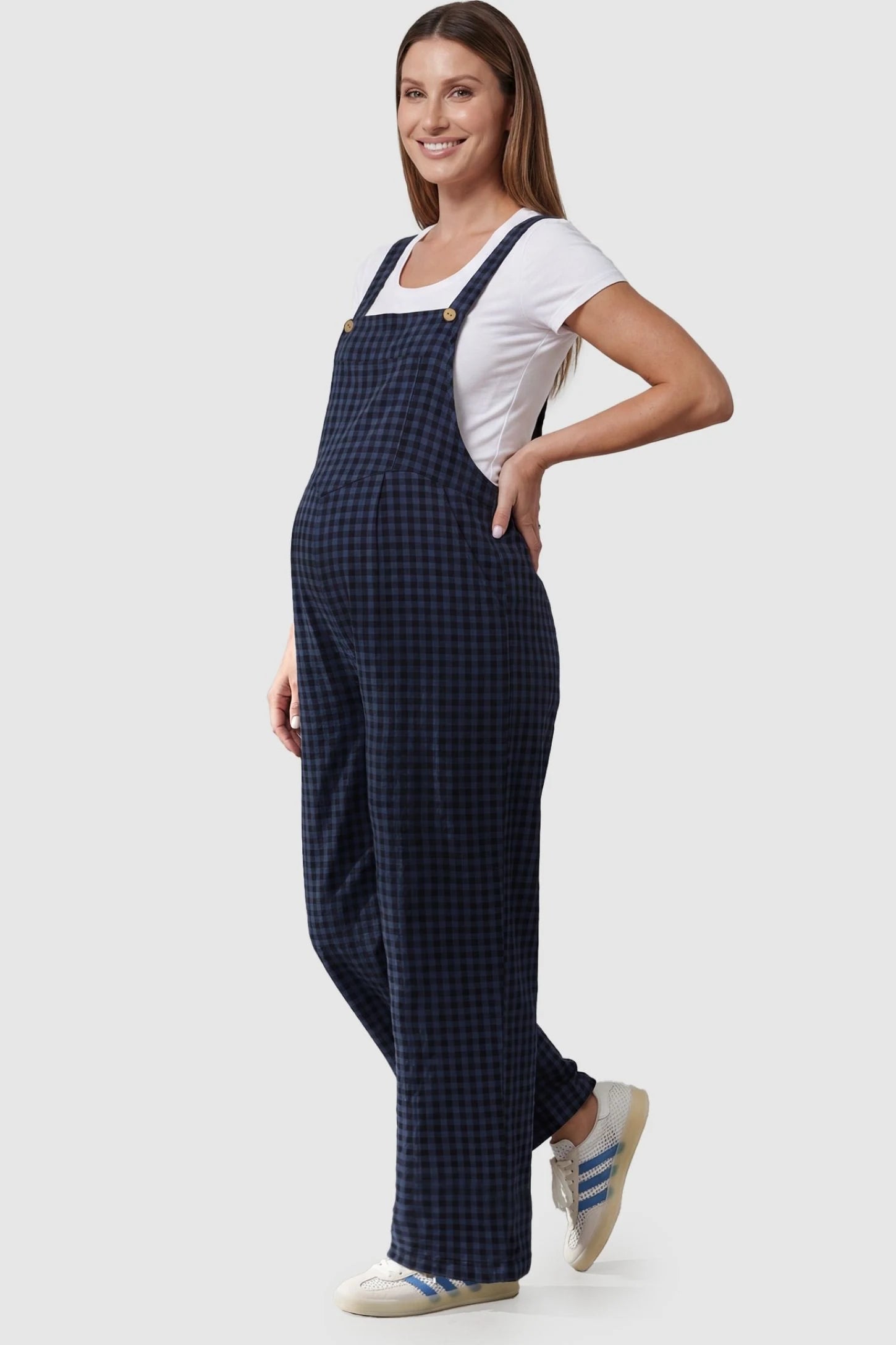 Plaid Square-Neck Button-Detail Maternity Jumpsuit Plaid Square-Neck Button-Detail Maternity Jumpsuit in Blue featuring wood-tone buttons on a pregnant model in a side view.