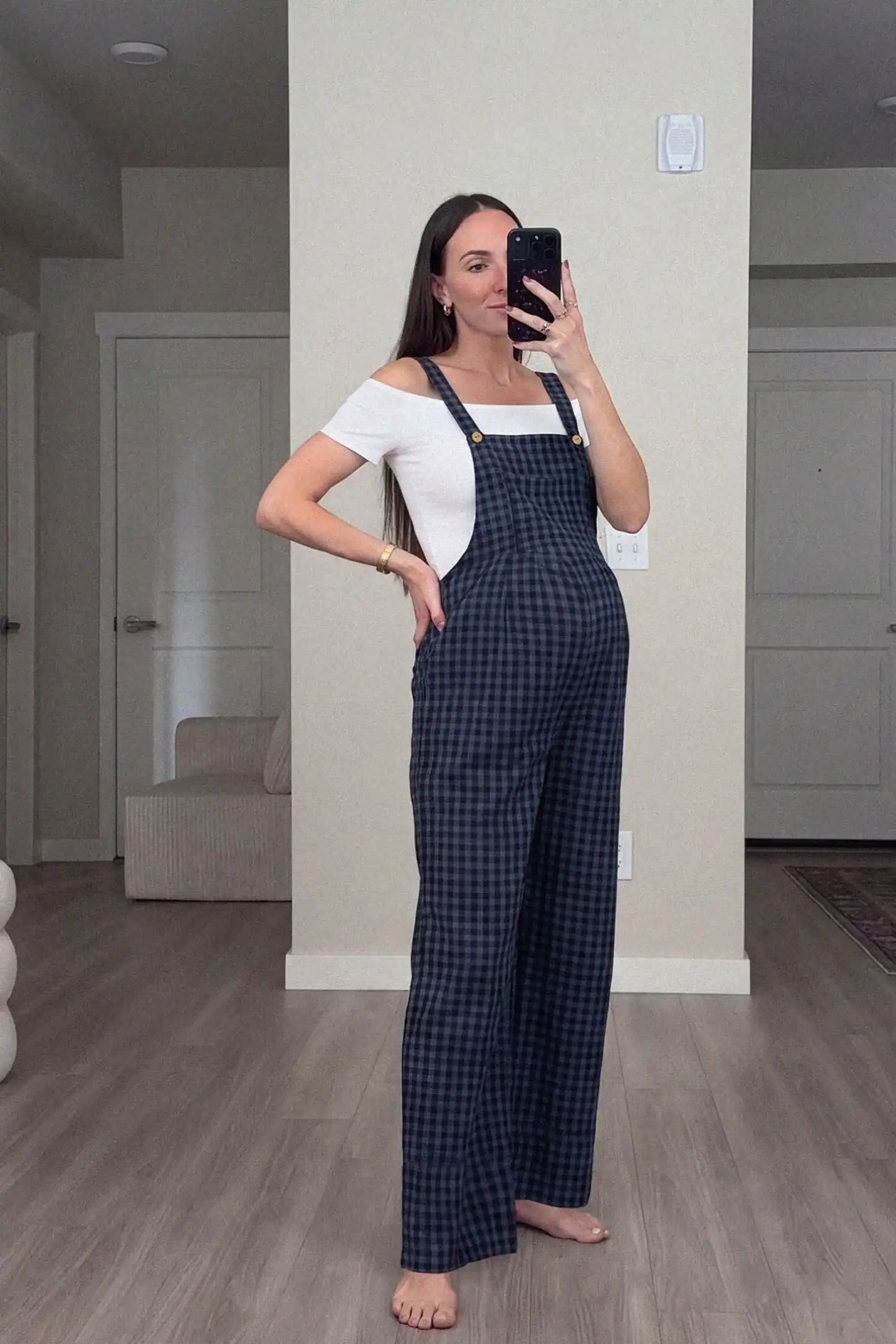 Plaid Square-Neck Button-Detail Maternity Jumpsuit Plaid Square-Neck Button-Detail Maternity Jumpsuit in Blue featuring a classic gingham print on a pregnant model in a home setting.