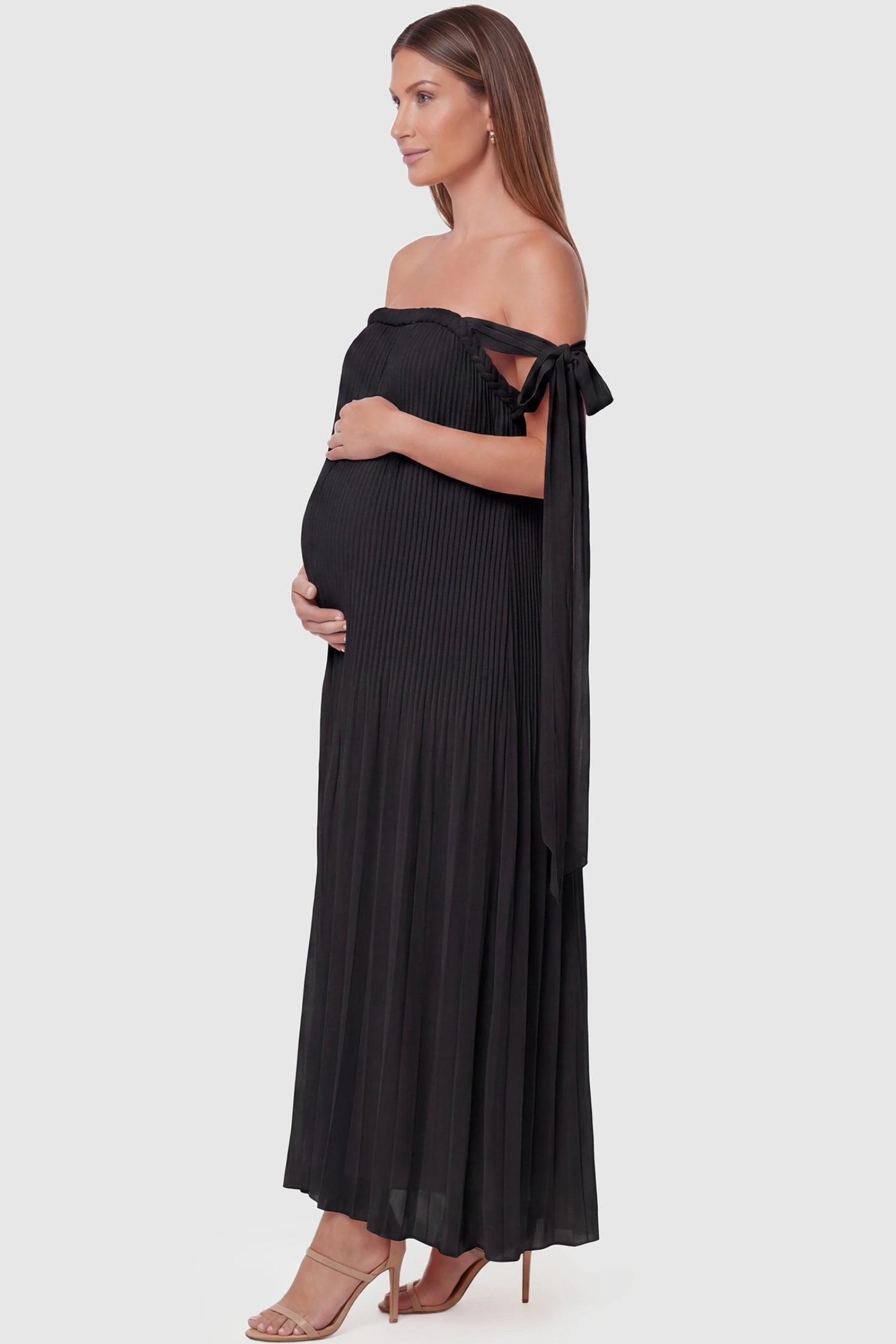 Pleated Braided Cold-Shoulder Maxi Maternity Gown Pleated Braided Cold-Shoulder Maxi Maternity Gown in Black featuring flowing pleated chiffon on a pregnant model, side view.