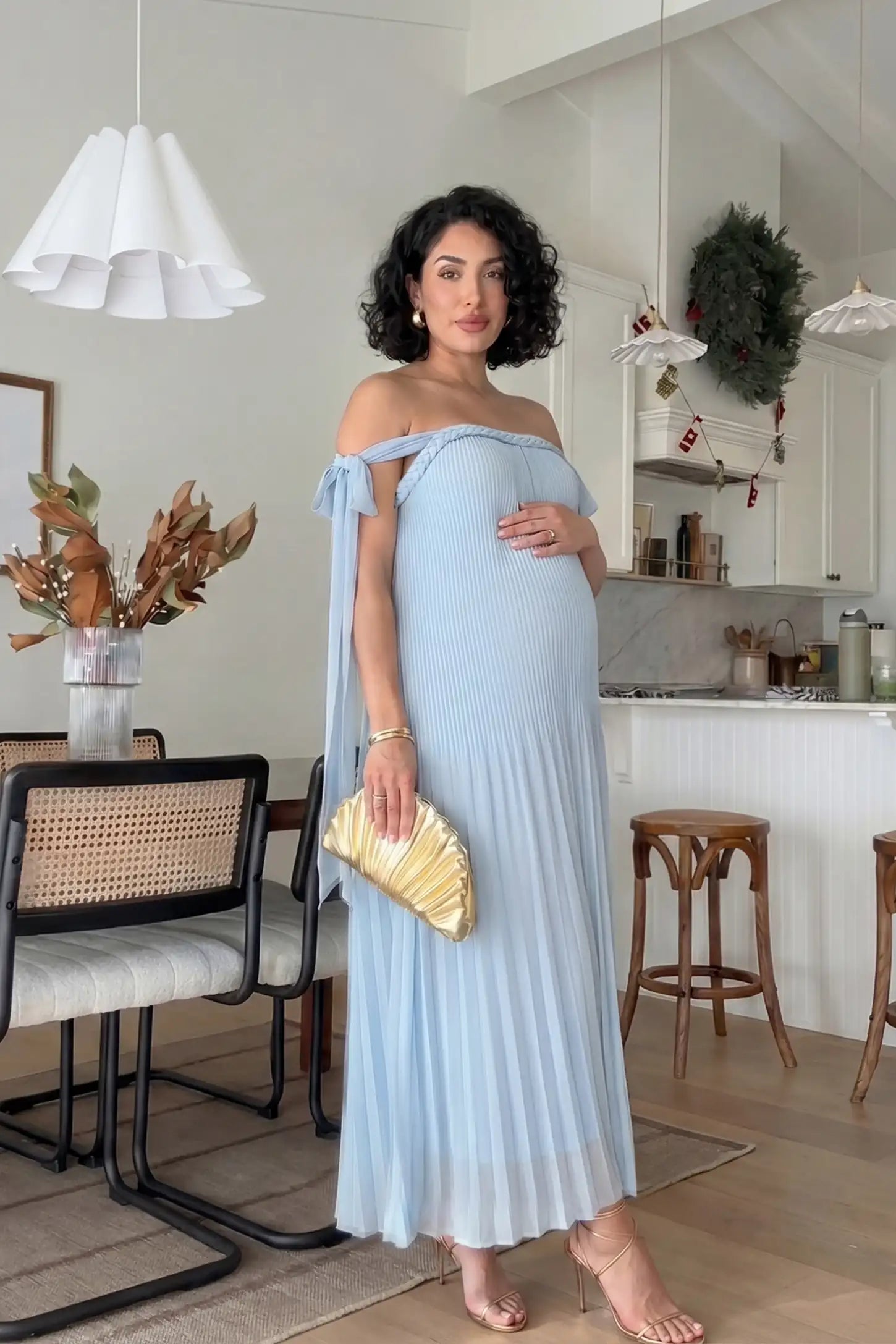 Pleated Braided Cold-Shoulder Maxi Maternity Gown Pleated Braided Cold-Shoulder Maxi Maternity Gown in Blue featuring soft pleated fabric on a pregnant model in an editorial lifestyle setting.