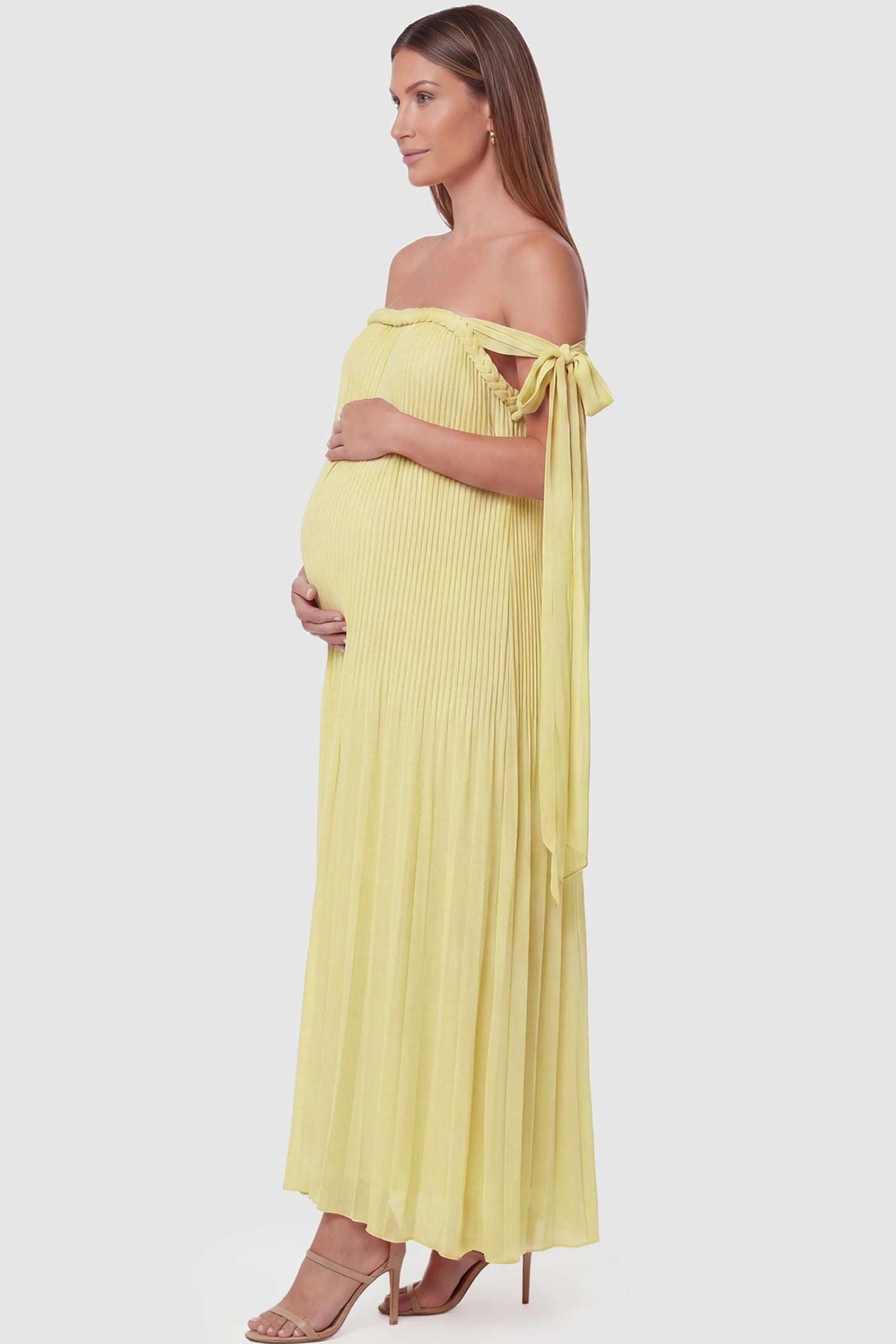 Pleated Braided Cold-Shoulder Maxi Maternity Gown Pleated Braided Cold-Shoulder Maxi Maternity Gown in Yellow featuring flowing pleated chiffon on a pregnant model, side view.
