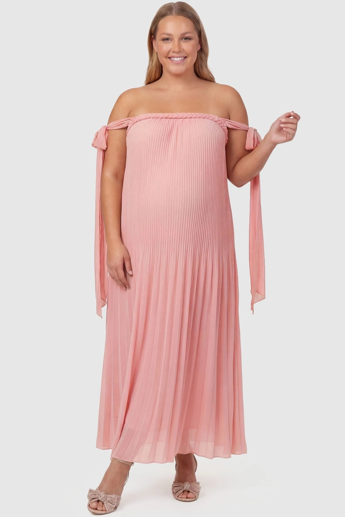 Pleated Braided Cold-Shoulder Maxi Maternity Gown Pleated Braided Cold-Shoulder Maxi Maternity Gown in Pink with pleated design and tie neckline, front view on a non plus-size model.