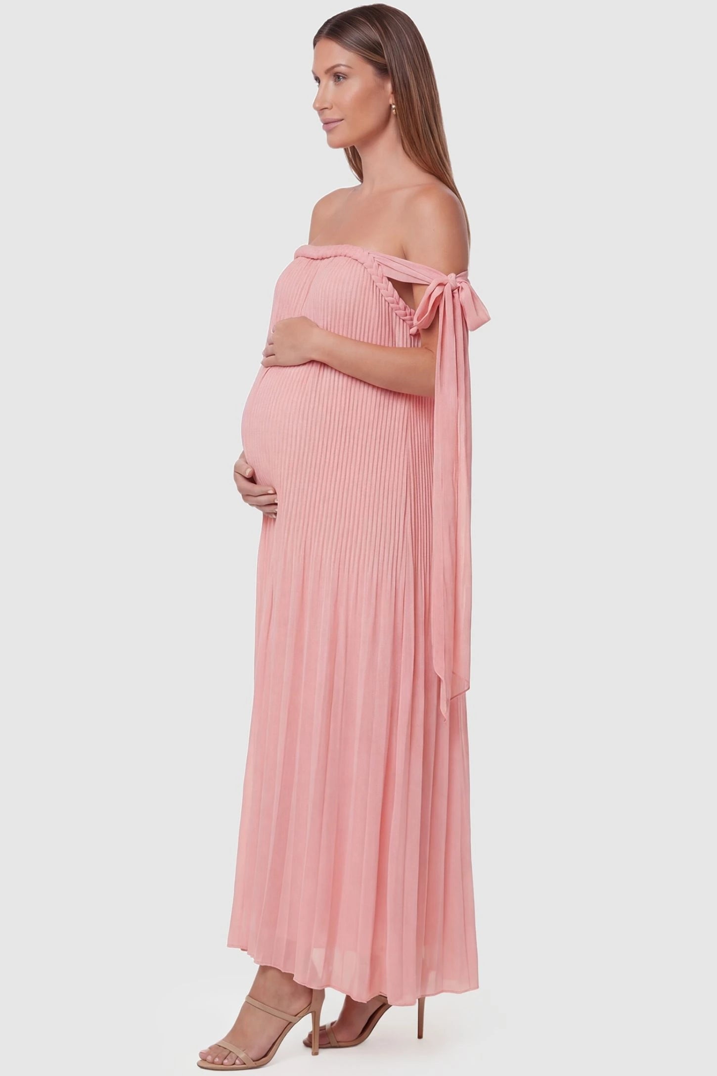 Pleated Braided Cold-Shoulder Maxi Maternity Gown Pleated Braided Cold-Shoulder Maxi Maternity Gown in Pink with flowy pleats and tie shoulders, side view on a pregnant model.