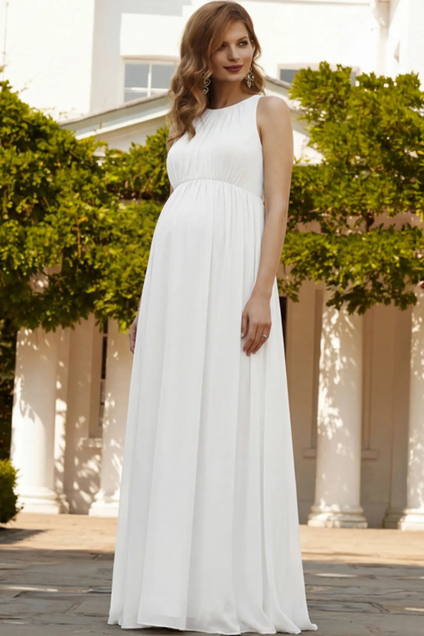 Pleated Mesh Sleeveless Maternity Photoshoot Dress Pleated Mesh Sleeveless Maternity Maxi Dress in white featuring an empire waist on a pregnant woman.