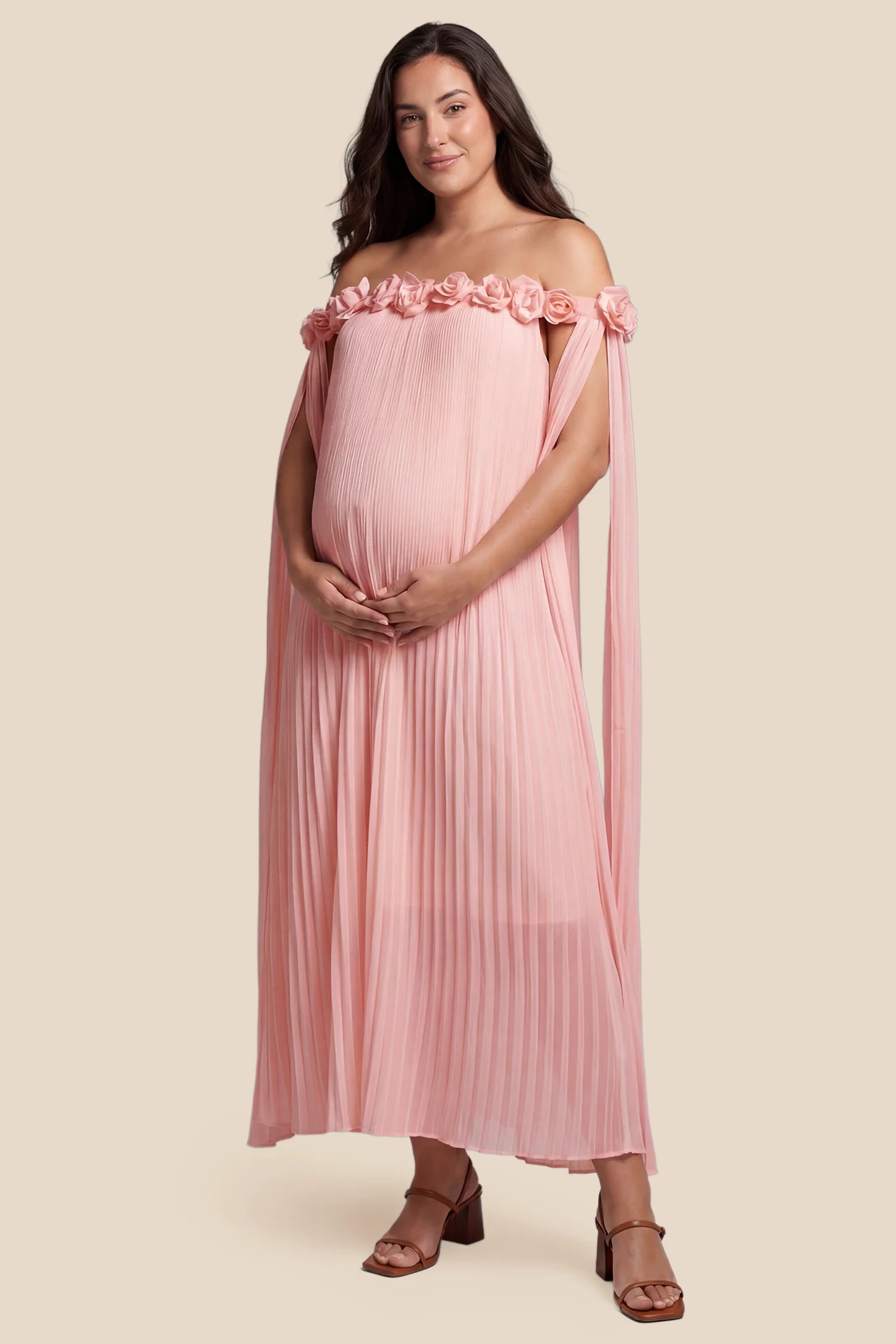 Pleated Off-Shoulder Maternity Gown with Rosettes Pleated Off-Shoulder Maternity Gown with Rosettes in Pink featuring an off-shoulder neckline and rosette accents, front view on a pregnant model.