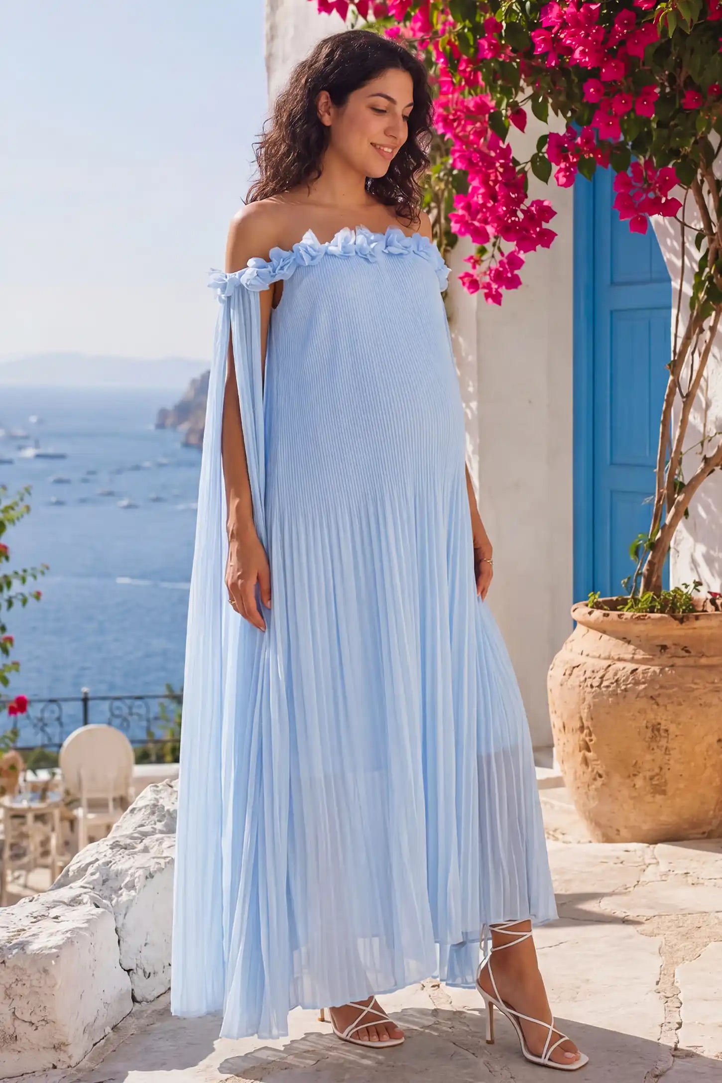 Pleated Off-Shoulder Maternity Gown with Rosettes Pleated Off-Shoulder Maternity Gown with Rosettes in Skye Blue with pleated details, lifestyle view on a pregnant model.