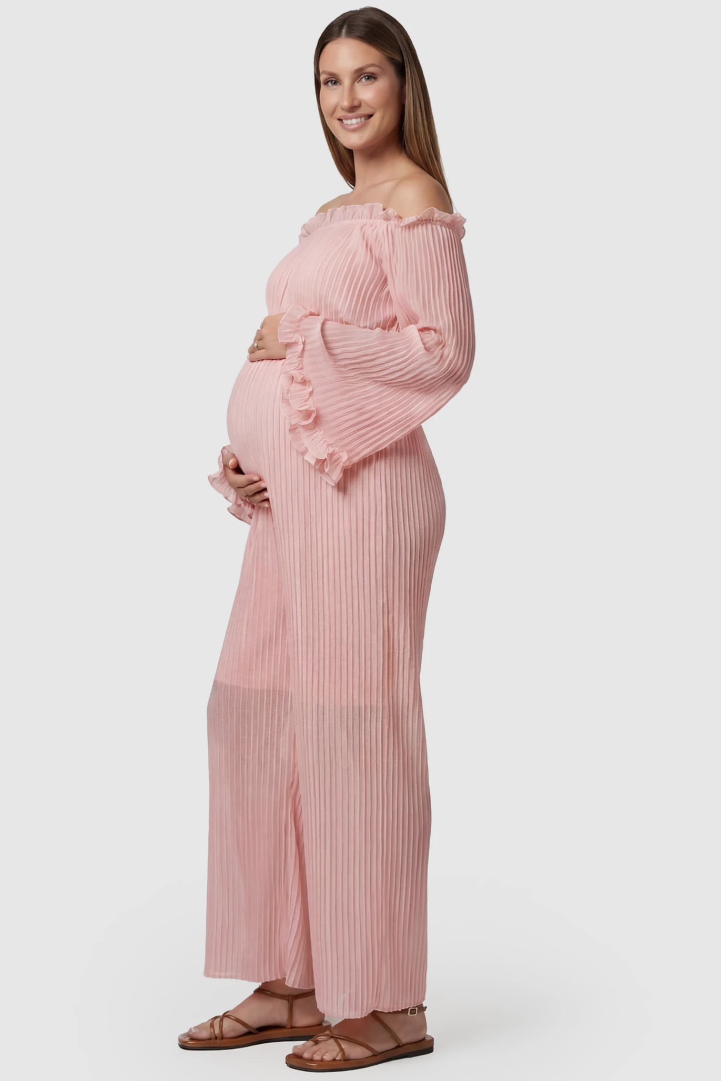 Pleated Off Shoulder Tie-Waist Maternity Jumpsuit Pleated Off Shoulder Tie-Waist Maternity Jumpsuit in Pink featuring a wide-leg silhouette on a pregnant model, side view.
