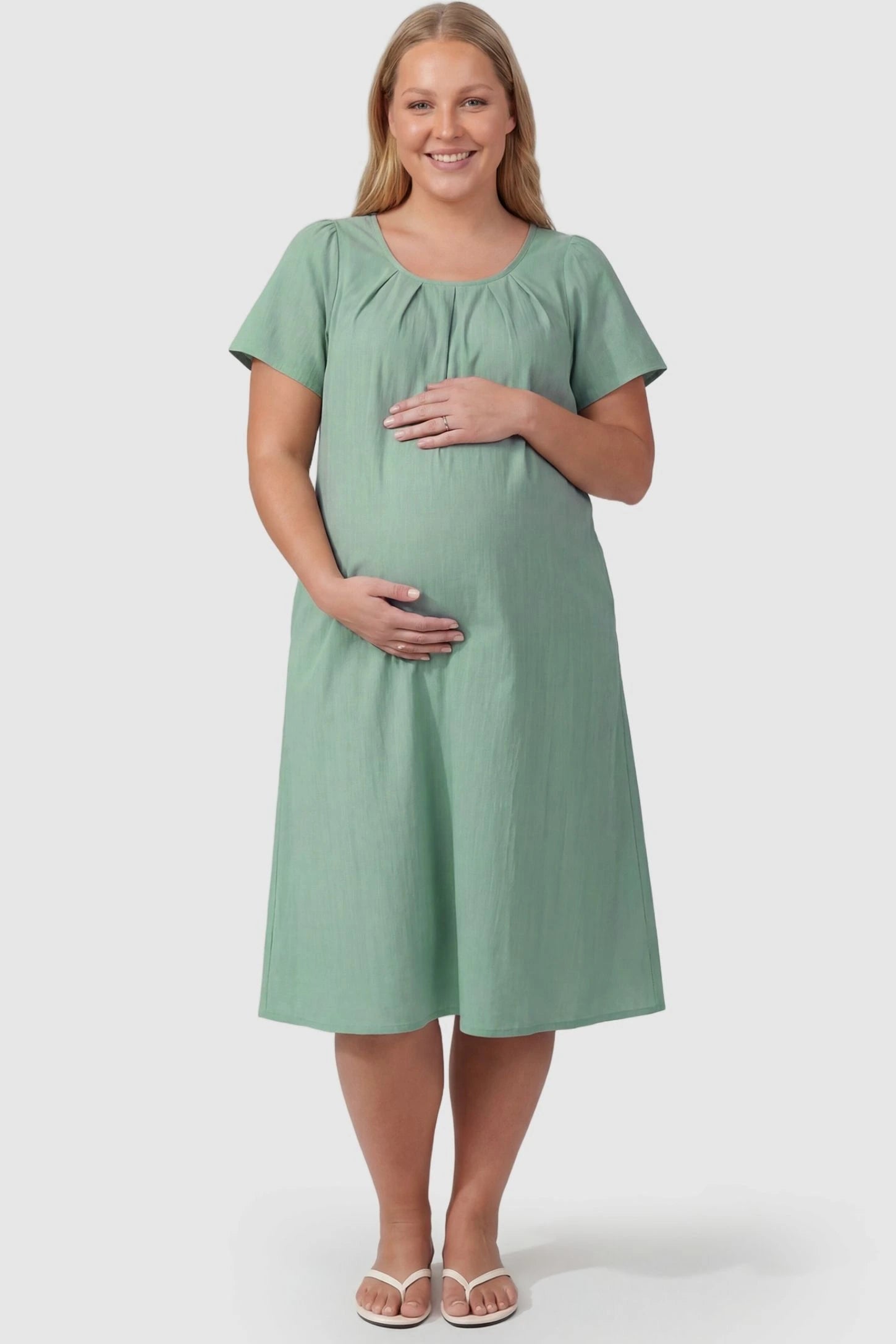 Pleated Round Neck Flowy Midi Maternity Dress Pleated Round Neck Flowy Midi Maternity Dress in Lake Blue featuring stretchy fabric on a plus size pregnant model, front view.