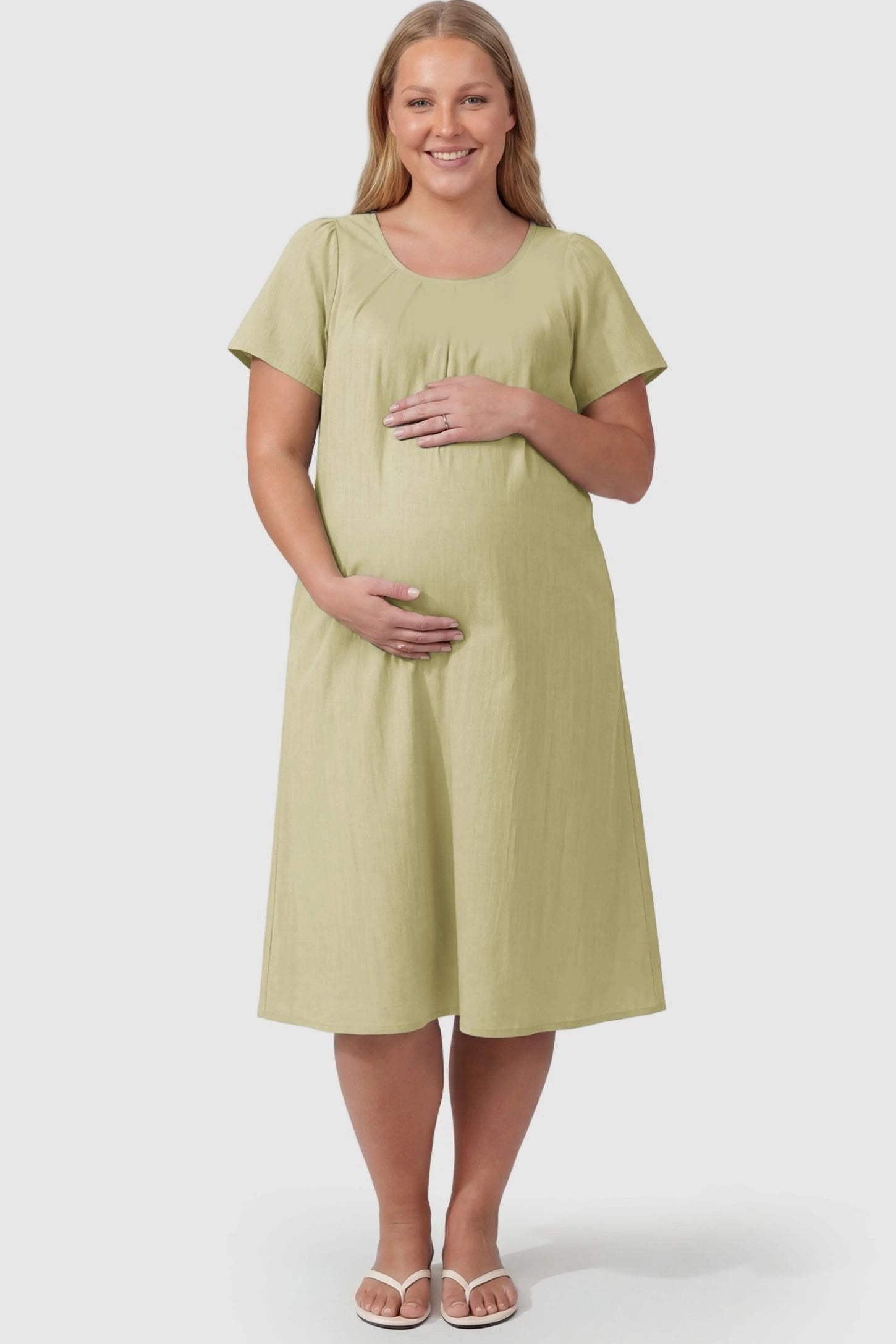 Pleated Round Neck Flowy Midi Maternity Dress Pleated Round Neck Flowy Midi Maternity Dress in Light Green featuring stretchy fabric on a plus size pregnant model, front view.