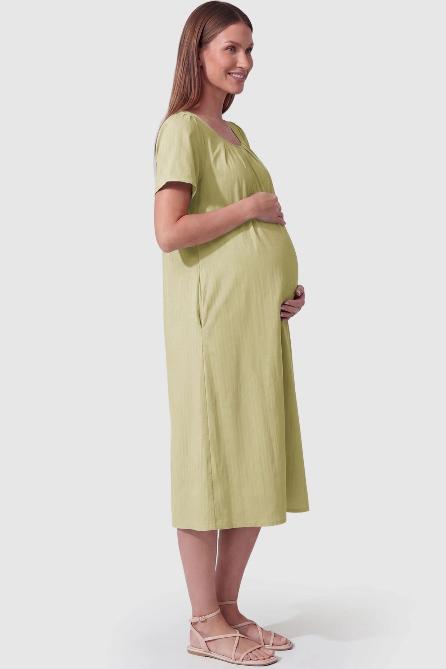 Pleated Round Neck Flowy Midi Maternity Dress Pleated Round Neck Flowy Midi Maternity Dress in Light Green featuring a flowy silhouette on a pregnant model, side view.