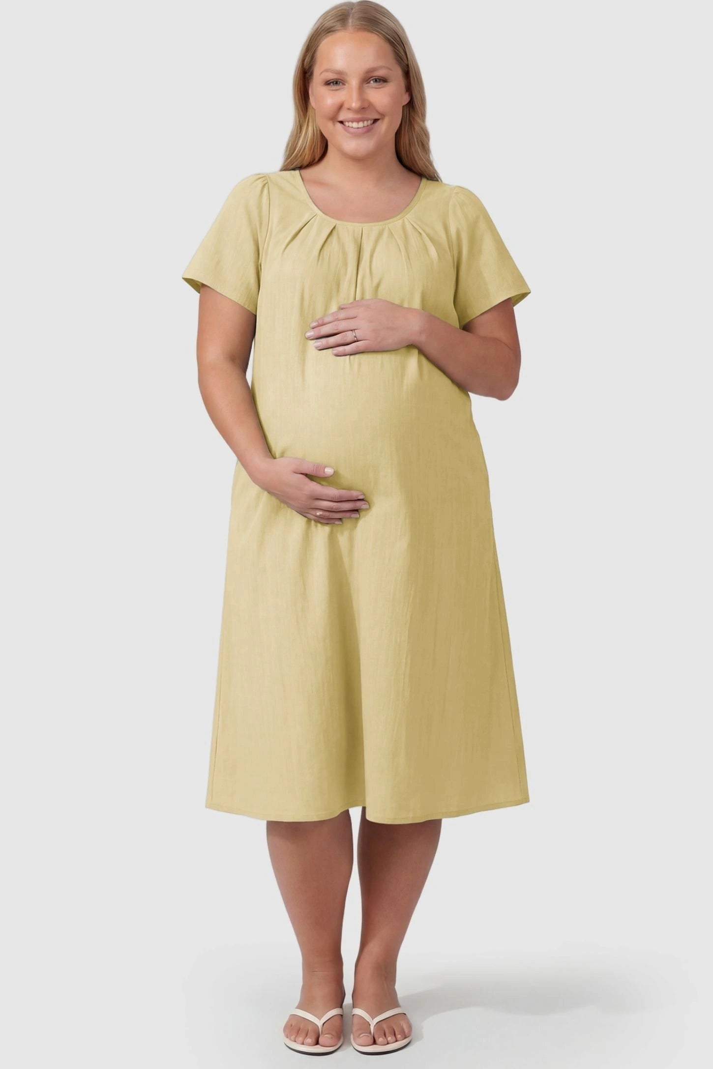 Pleated Round Neck Flowy Midi Maternity Dress Pleated Round Neck Flowy Midi Maternity Dress in Yellow featuring stretchy fabric on a plus size pregnant model, front view.
