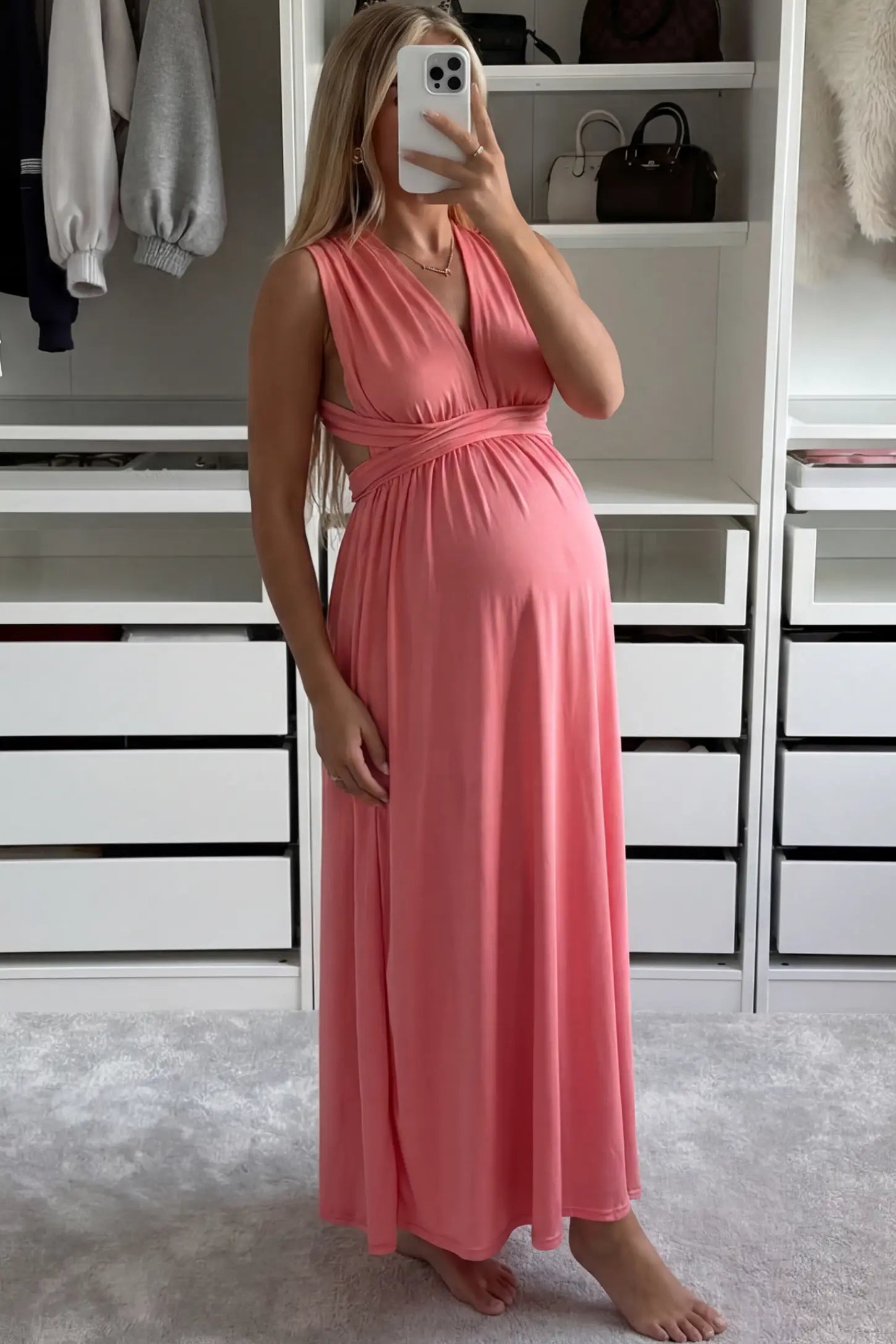 Plunging Halter Empire Waist Maternity Maxi Dress Plunging Halter Empire Waist Maternity Maxi Dress in Pink featuring high-stretch fabric on a pregnant model in a home setting showing front.