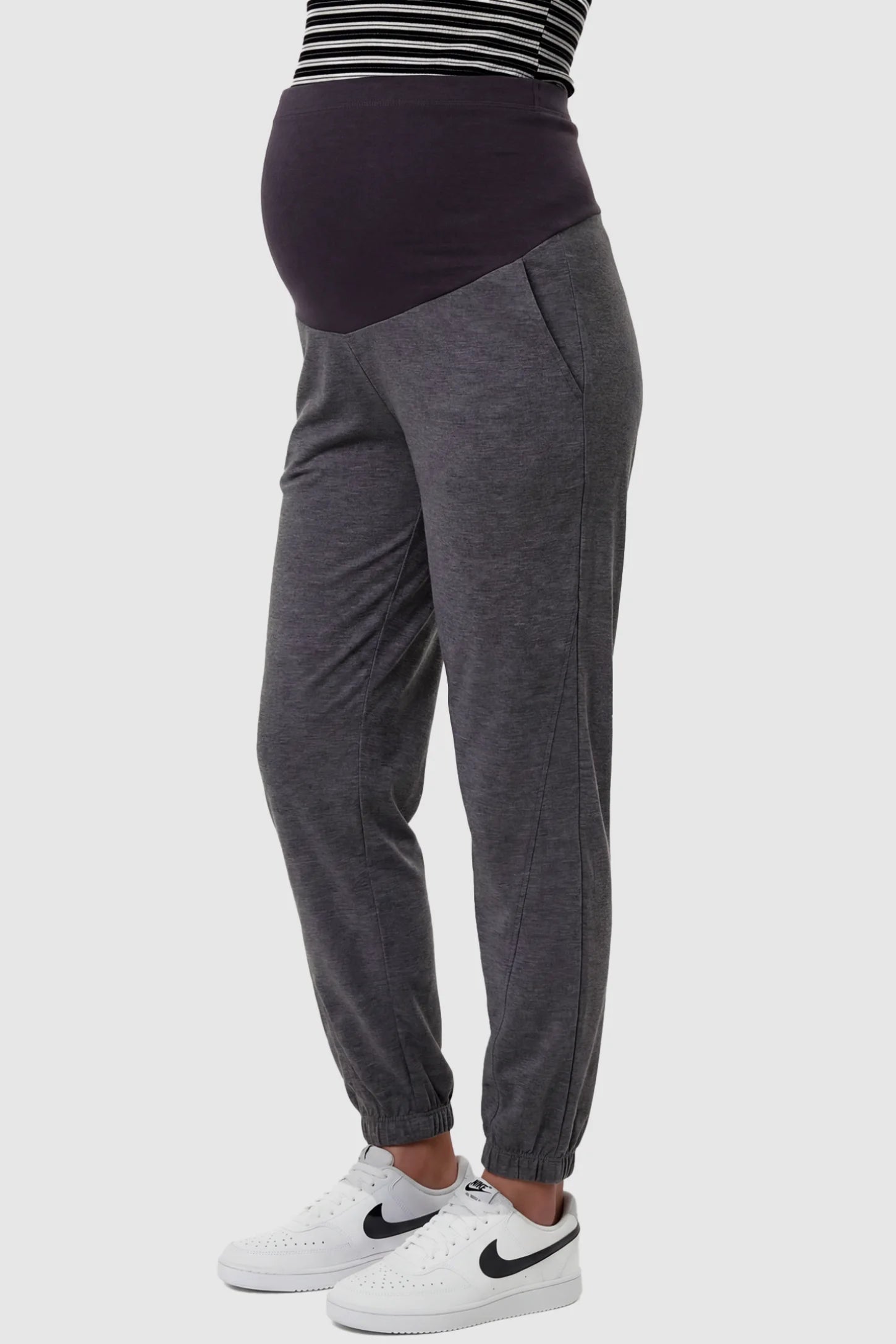 Full Panel Pocketed Maternity Jogger Pants Full Panel Pocketed Maternity Jogger Pants in Dark Gray featuring a jersey belly panel on a pregnant model, side view.