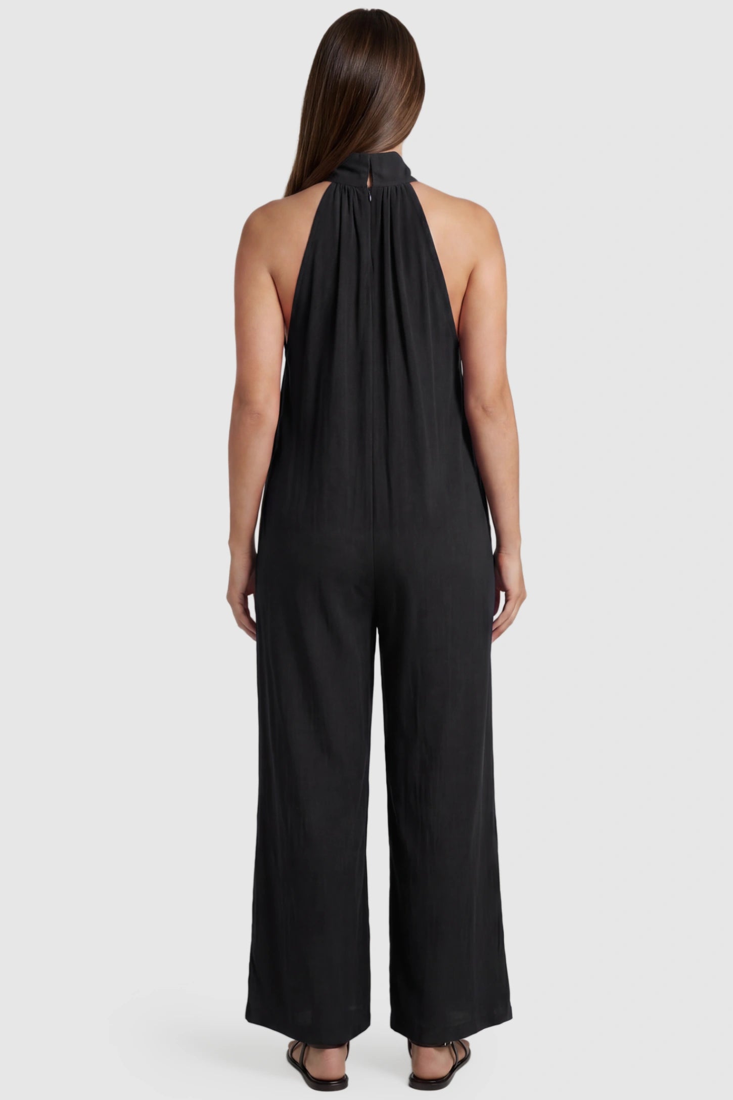 Pocketed Mock Neck Sleeveless Maternity Jumpsuit Pocketed Mock Neck Sleeveless Maternity Jumpsuit in black featuring a high gathered neckline, side pockets shown on a pregnant model, back view.