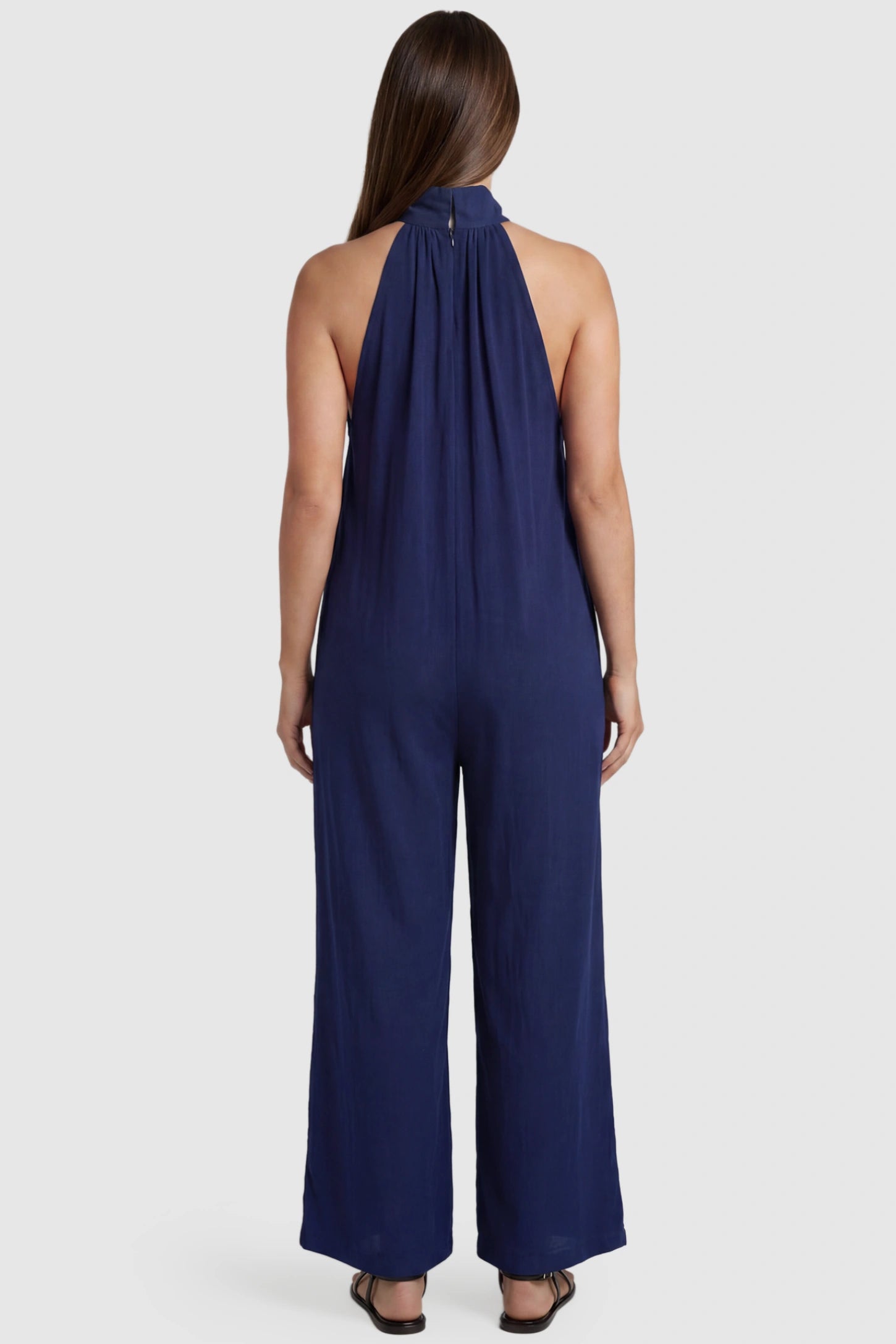 Pocketed Mock Neck Sleeveless Maternity Jumpsuit Pocketed Mock Neck Sleeveless Maternity Jumpsuit in blue featuring a high gathered neckline, side pockets shown on a pregnant model, back view.