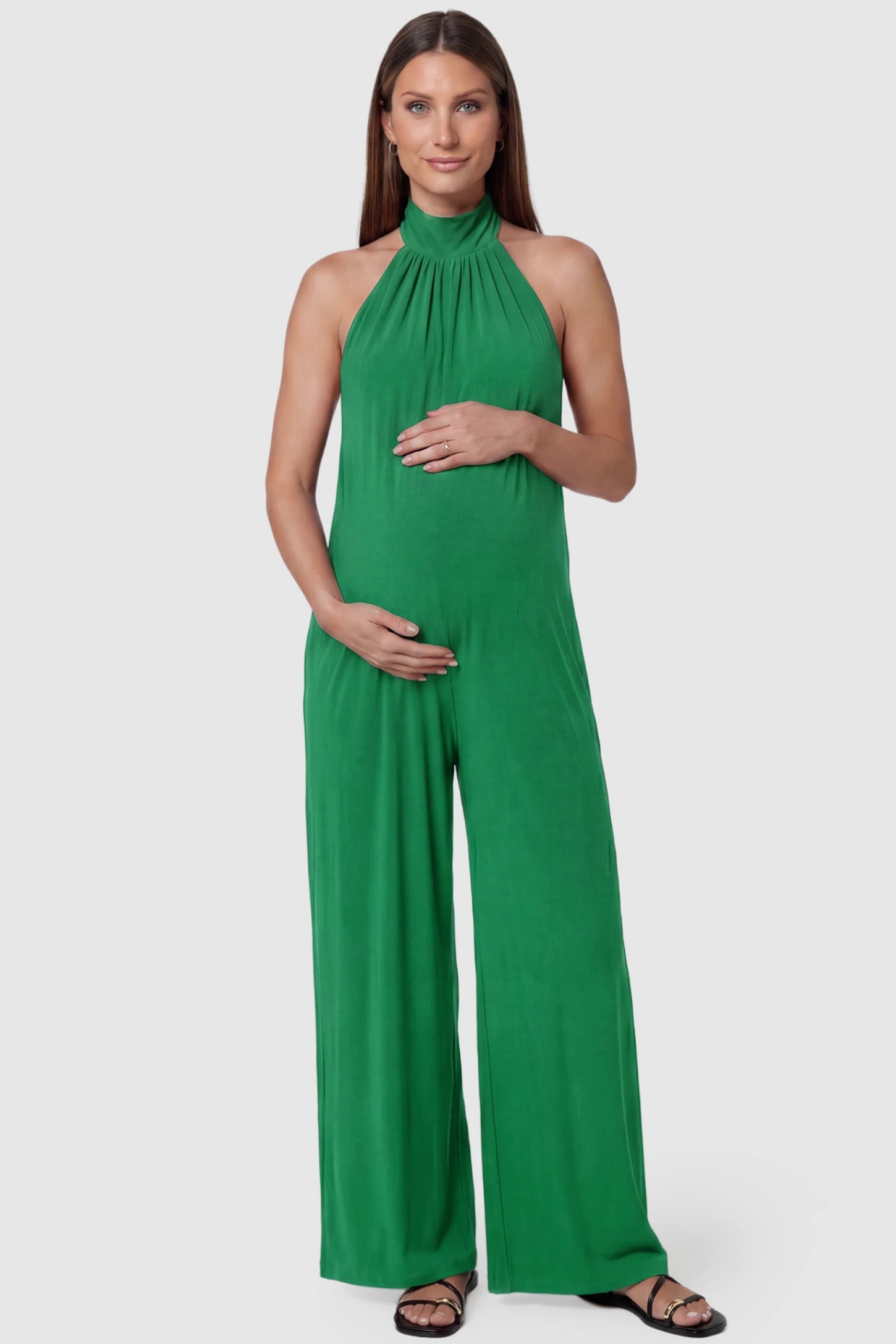 Pocketed Mock Neck Sleeveless Maternity Jumpsuit Pocketed Mock Neck Sleeveless Maternity Jumpsuit in green featuring a high gathered neckline, side pockets shown on a pregnant model, front view.