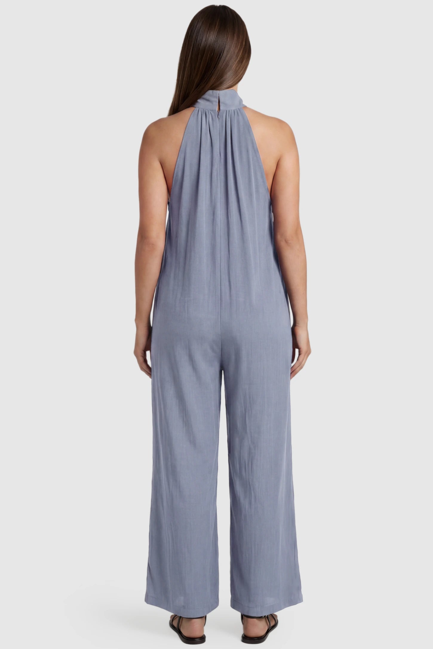 Pocketed Mock Neck Sleeveless Maternity Jumpsuit Pocketed Mock Neck Sleeveless Maternity Jumpsuit in light blue featuring a high gathered neckline, side pockets shown on a pregnant model, back view.