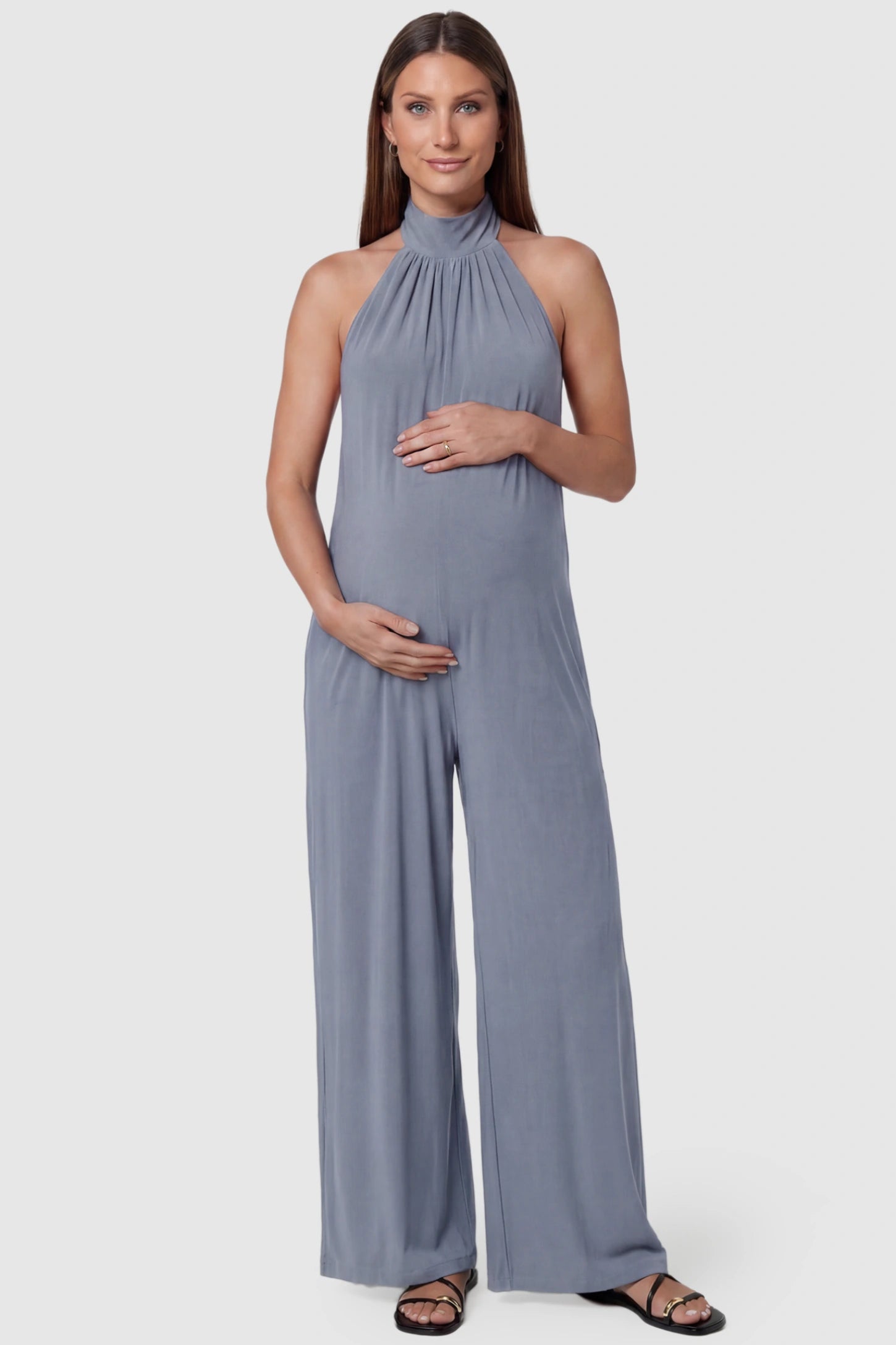 Pocketed Mock Neck Sleeveless Maternity Jumpsuit Pocketed Mock Neck Sleeveless Maternity Jumpsuit in light blue featuring a high gathered neckline, side pockets shown on a pregnant model, front view.