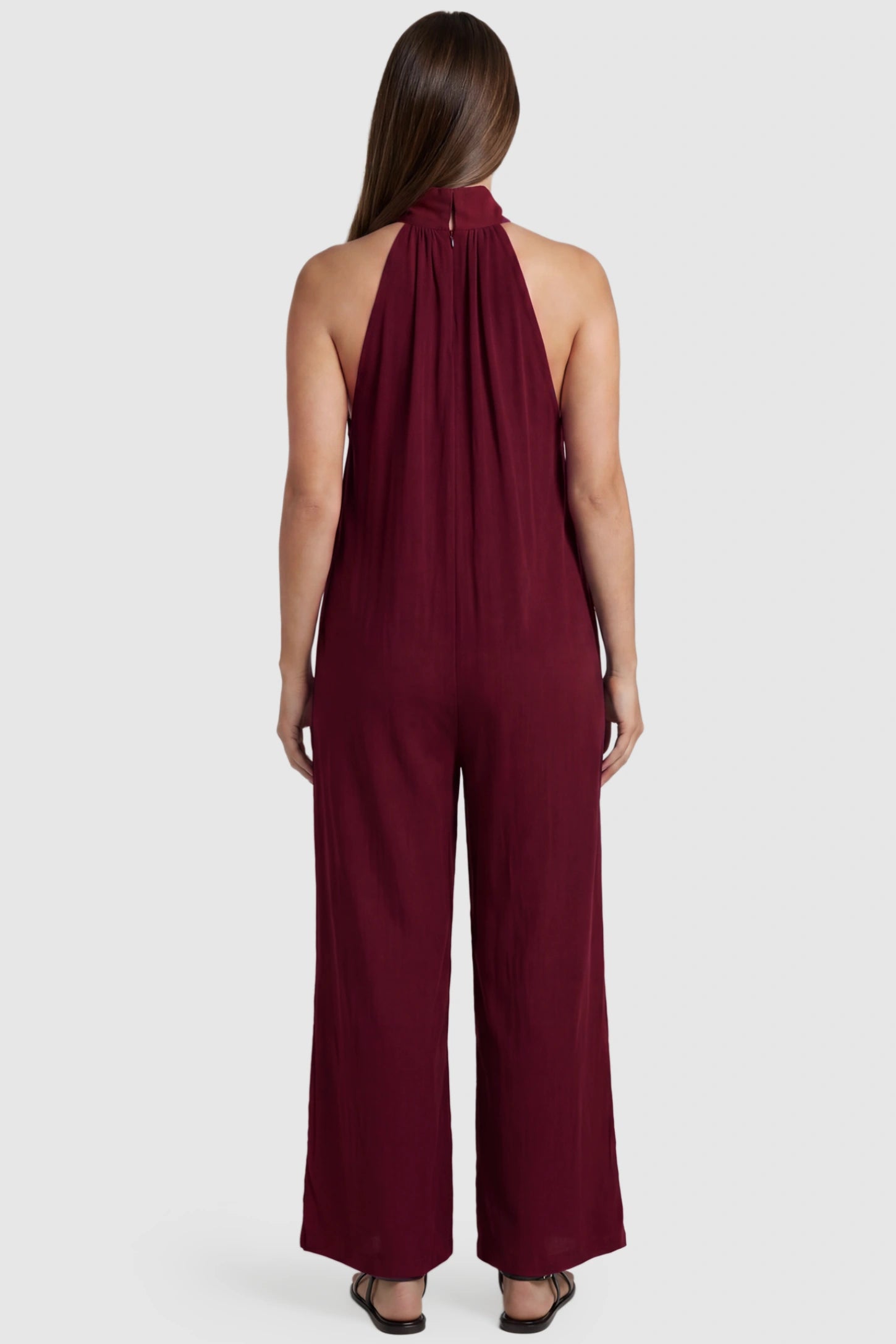 Pocketed Mock Neck Sleeveless Maternity Jumpsuit Pocketed Mock Neck Sleeveless Maternity Jumpsuit in rose red featuring a high gathered neckline, side pockets shown on a pregnant model, back view.