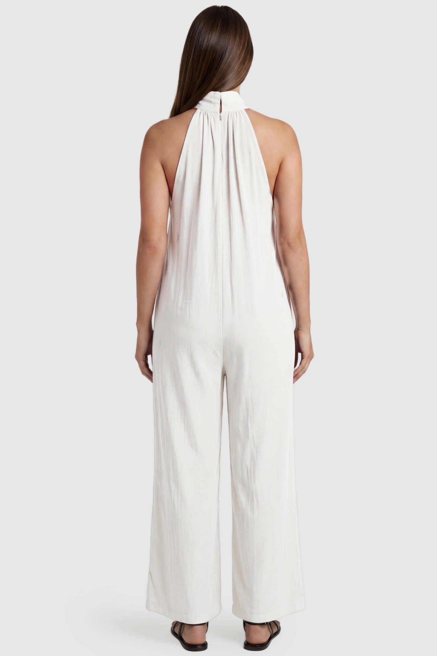 Pocketed Mock Neck Sleeveless Maternity Jumpsuit Pocketed Mock Neck Sleeveless Maternity Jumpsuit in white featuring a high gathered neckline, side pockets shown on a pregnant model, back view.