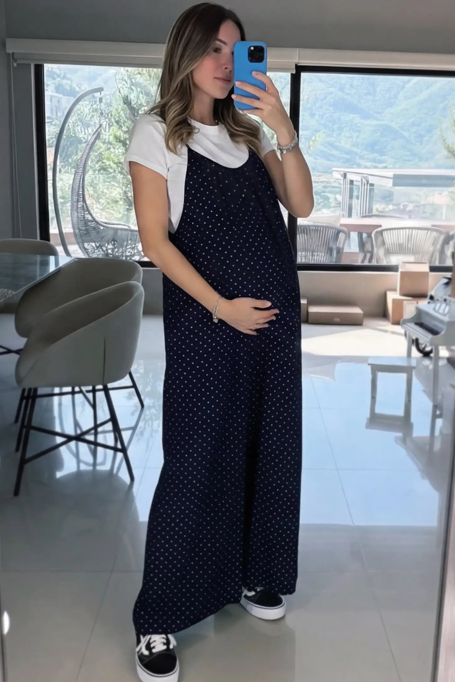 Pocketed Spaghetti Strap Wide Leg Maternity Jumpsuit Pocketed Spaghetti Strap Wide Leg Maternity Jumpsuit in Blue featuring loose fitting silhouette and pockets on a pregnant model in indoor setting, front view.