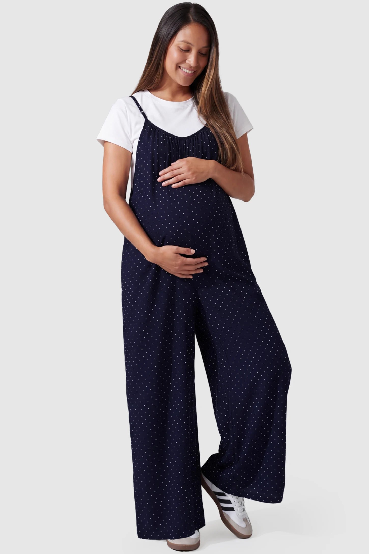 Pocketed Spaghetti Strap Wide Leg Maternity Jumpsuit in Blue featuring loose fitting silhouette and pockets on a pregnant model, front view.