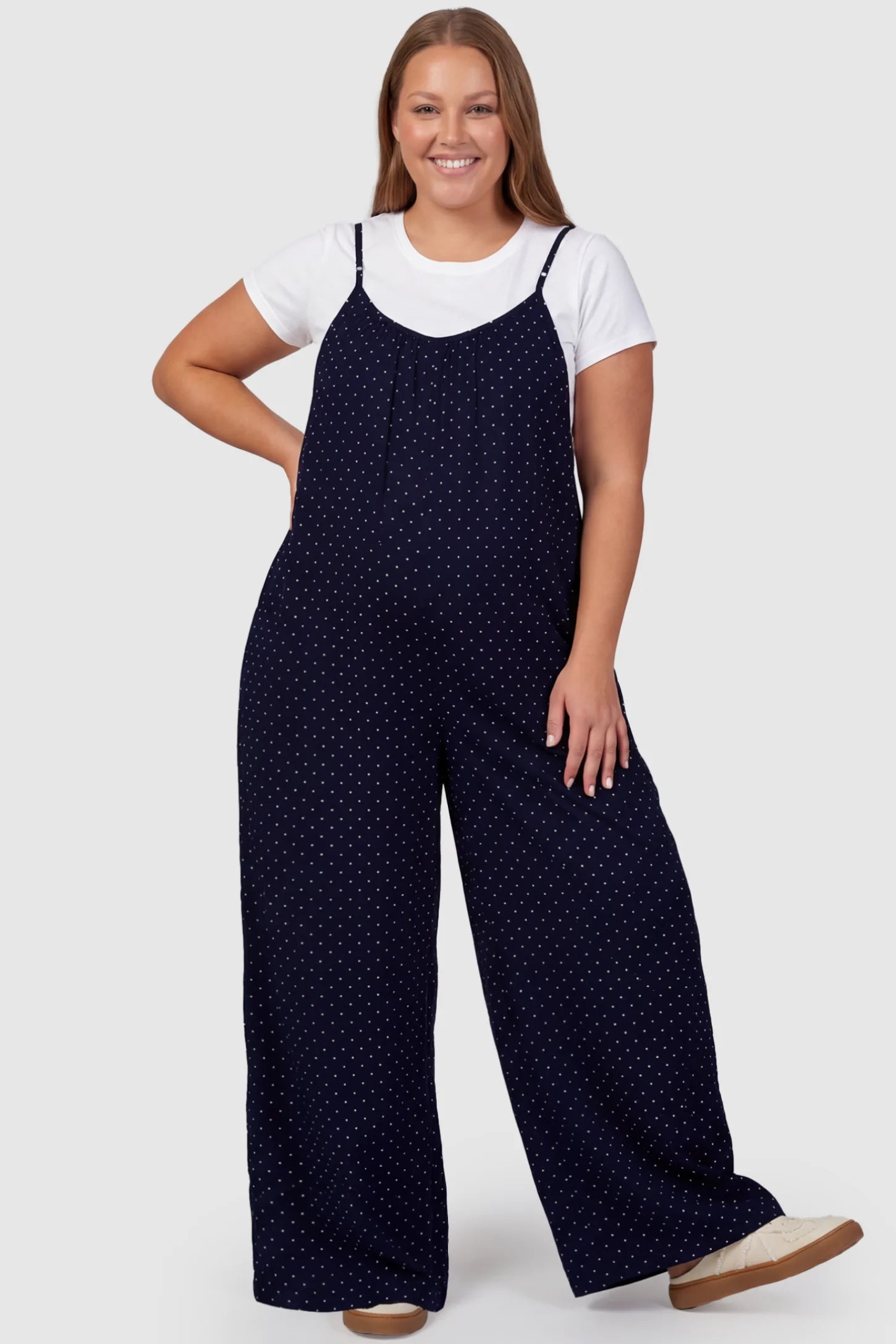 Pocketed Spaghetti Strap Wide Leg Maternity Jumpsuit Pocketed Spaghetti Strap Wide Leg Maternity Jumpsuit in Blue featuring loose fitting silhouette and pockets on a plus size pregnant model, front view.