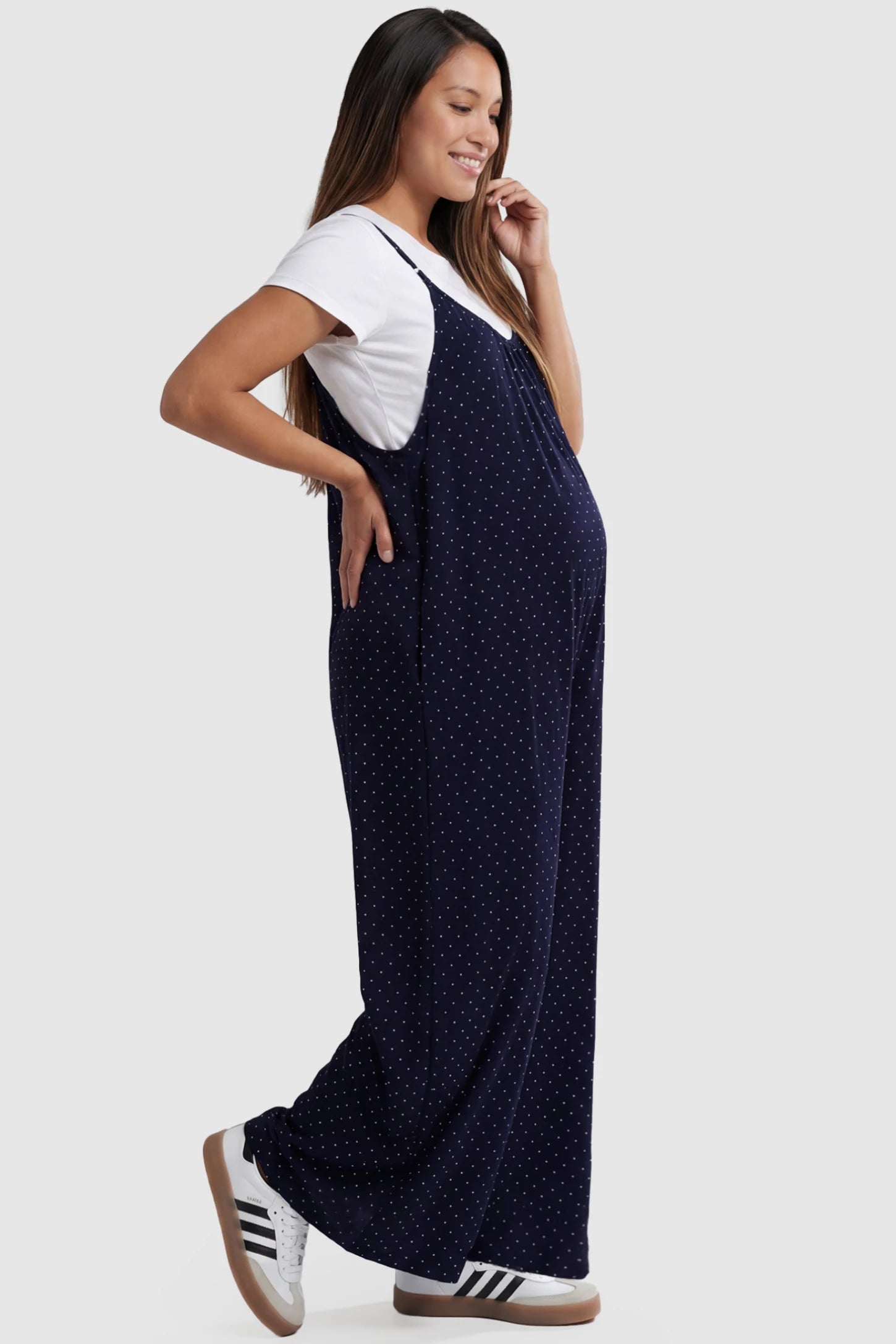 Pocketed Spaghetti Strap Wide Leg Maternity Jumpsuit Pocketed Spaghetti Strap Wide Leg Maternity Jumpsuit in Blue featuring loose fitting silhouette and pockets on a pregnant model, side view.