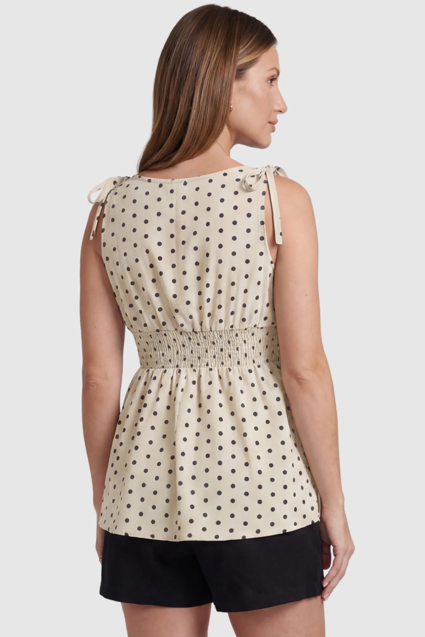 Polka Dot Round Neck Flowy Maternity Top Polka Dot Flowy Maternity Top in Beige featuring a smocked elastic waistband and shoulder ties on a pregnant model, back view.