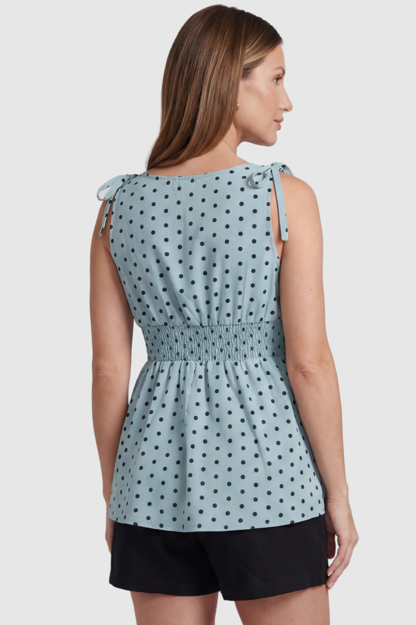 Polka Dot Round Neck Flowy Maternity Top Polka Dot Flowy Maternity Top in Blue featuring a smocked elastic waistband and shoulder ties on a pregnant model, back view.