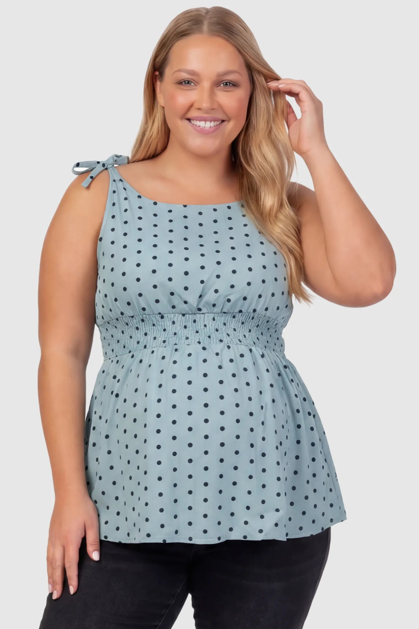 Polka Dot Round Neck Flowy Maternity Top Polka Dot Flowy Maternity Top in Blue featuring a smocked elastic waistband and shoulder ties on a plus size pregnant model, front view.