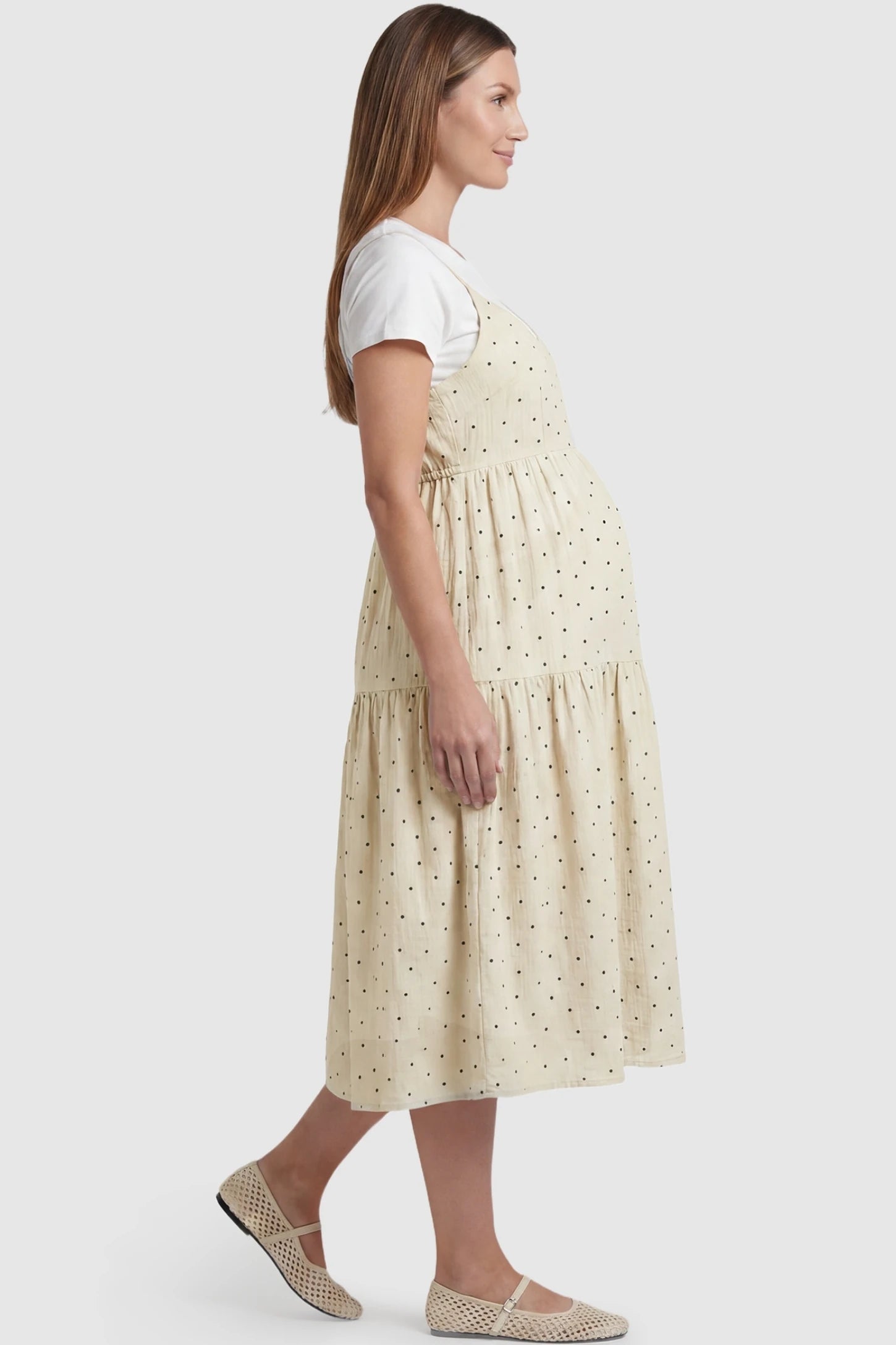 Polka Dot Round Neck Tiered Midi Maternity Dress Polka Dot Round Neck Tiered Midi Maternity Dress in Beige featuring an adjustable back tie and flowing tiered skirt on a pregnant model, side view.