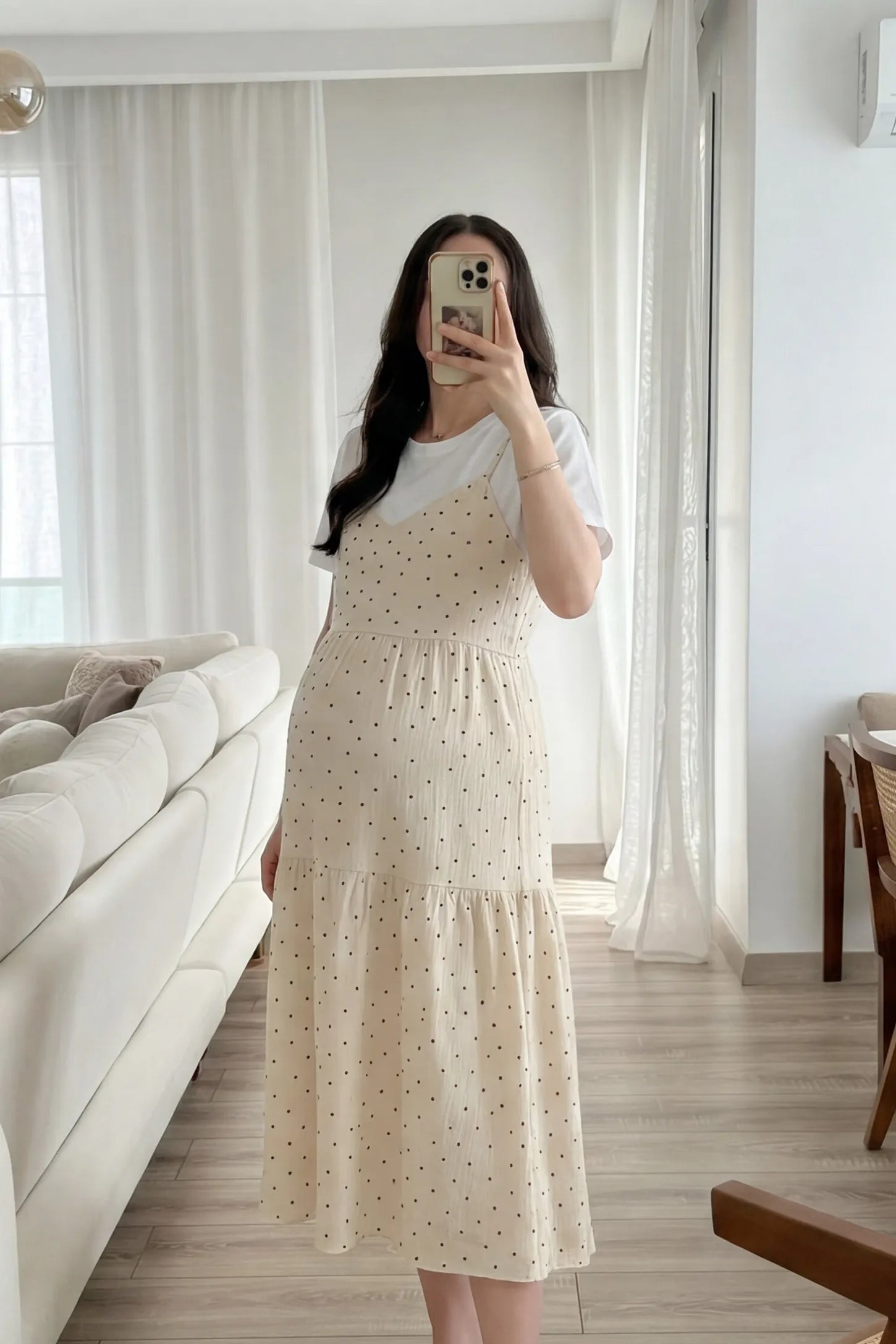 Polka Dot Round Neck Tiered Midi Maternity Dress Polka Dot Round Neck Tiered Midi Maternity Dress in Beige featuring a relaxed tiered silhouette layered over a white tee on a pregnant model, mirror selfie view.