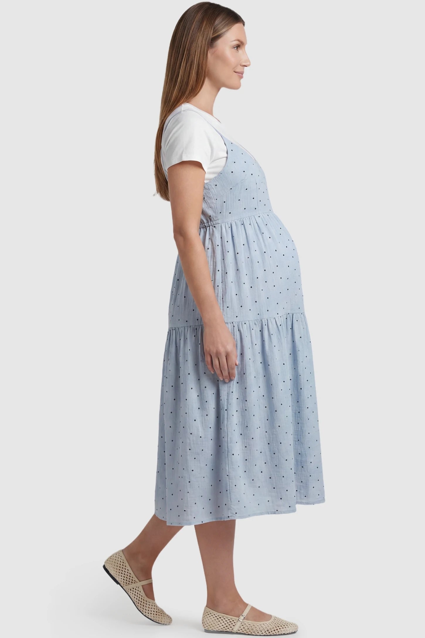 Polka Dot Round Neck Tiered Midi Maternity Dress Polka Dot Round Neck Tiered Midi Maternity Dress in Blue featuring a flowy tiered silhouette with room for a growing bump on a pregnant model, side view.