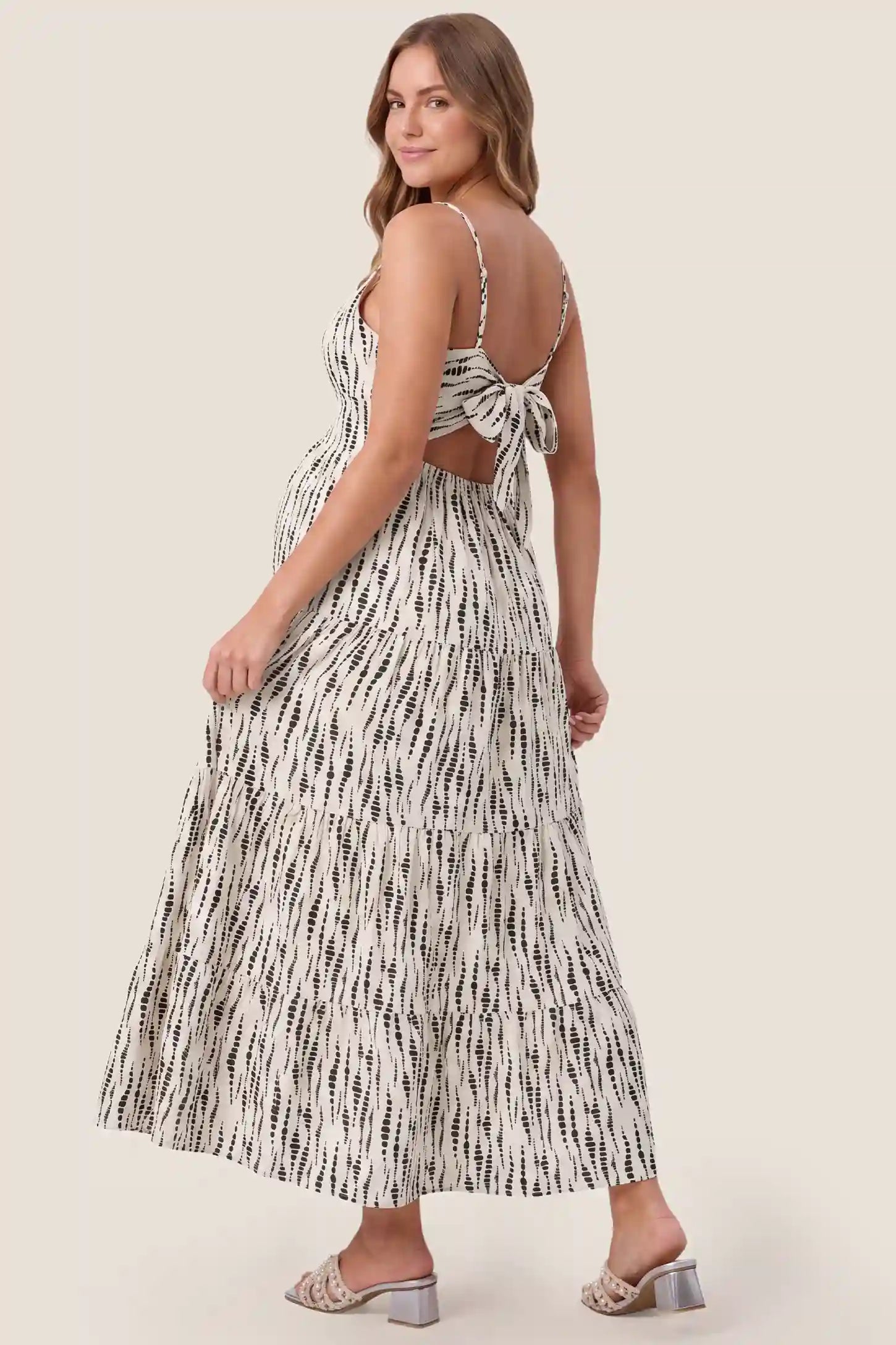 Print Tiered Cami Maternity Maxi Dress Print Tiered Cami Maternity Maxi Dress in Ivory Dash Print showcasing the flowy tiered back drape, back view on a pregnant model.