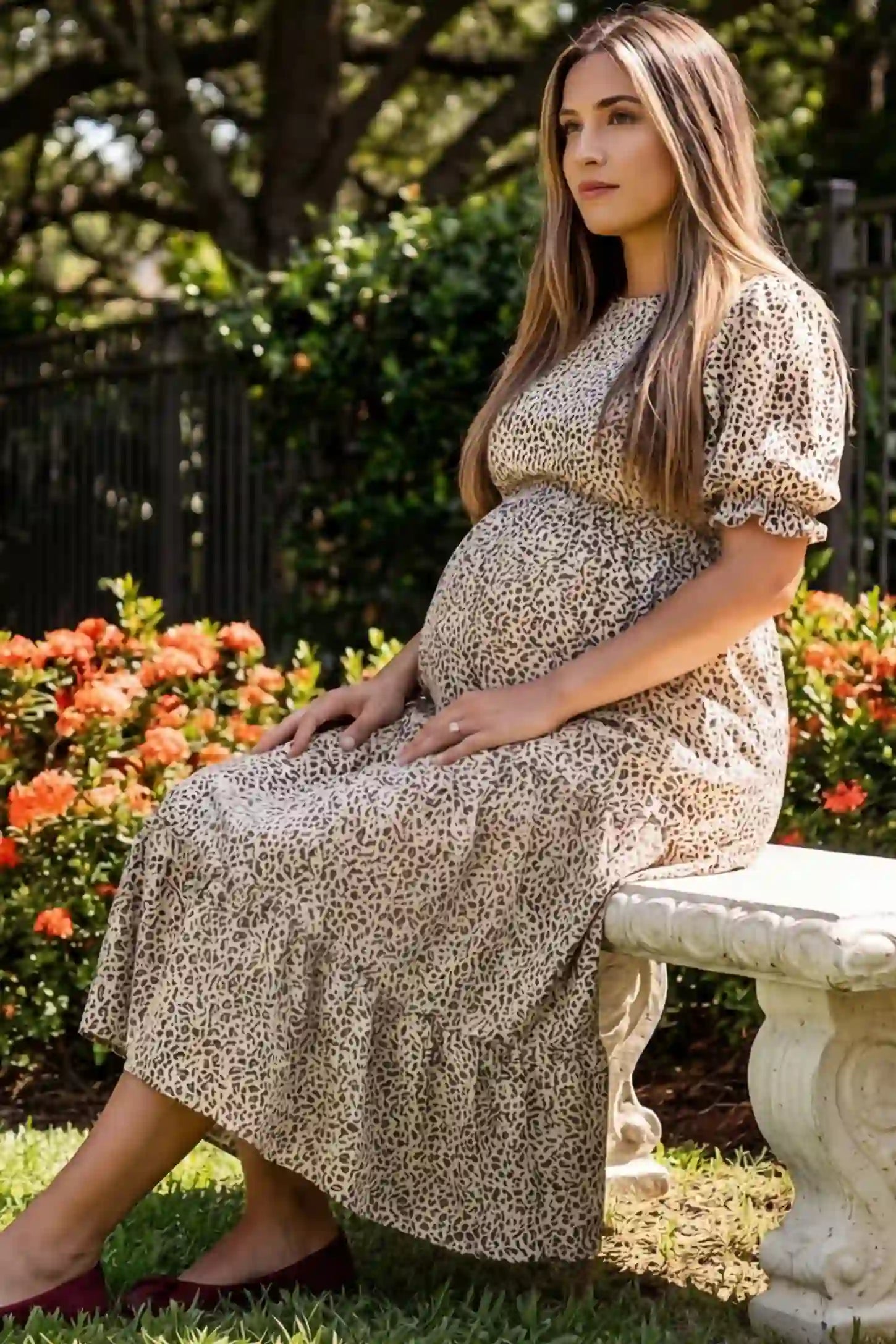 Printed Short Sleeve Tiered Maternity Midi Dress Printed Short Sleeve Tiered Maternity Midi Dress in apricot featuring round neck, tiered A-line skirt on a pregnant woman in outdoor setting, side view.