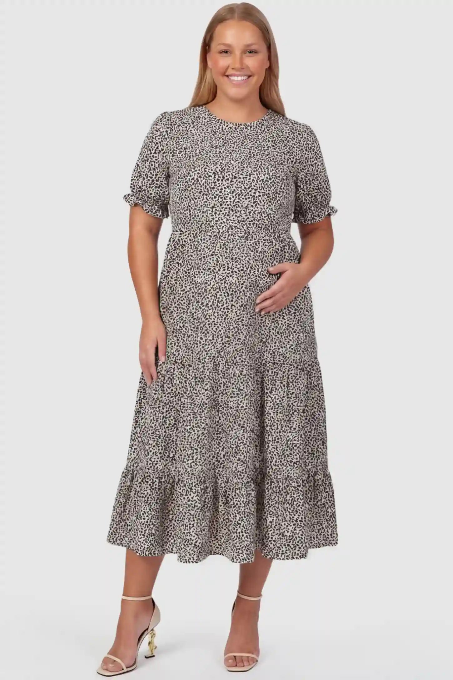 Printed Short Sleeve Tiered Maternity Midi Dress Printed Short Sleeve Tiered Maternity Midi Dress in apricot featuring round neck, tiered A-line skirt on a plus size pregnant model, front view.