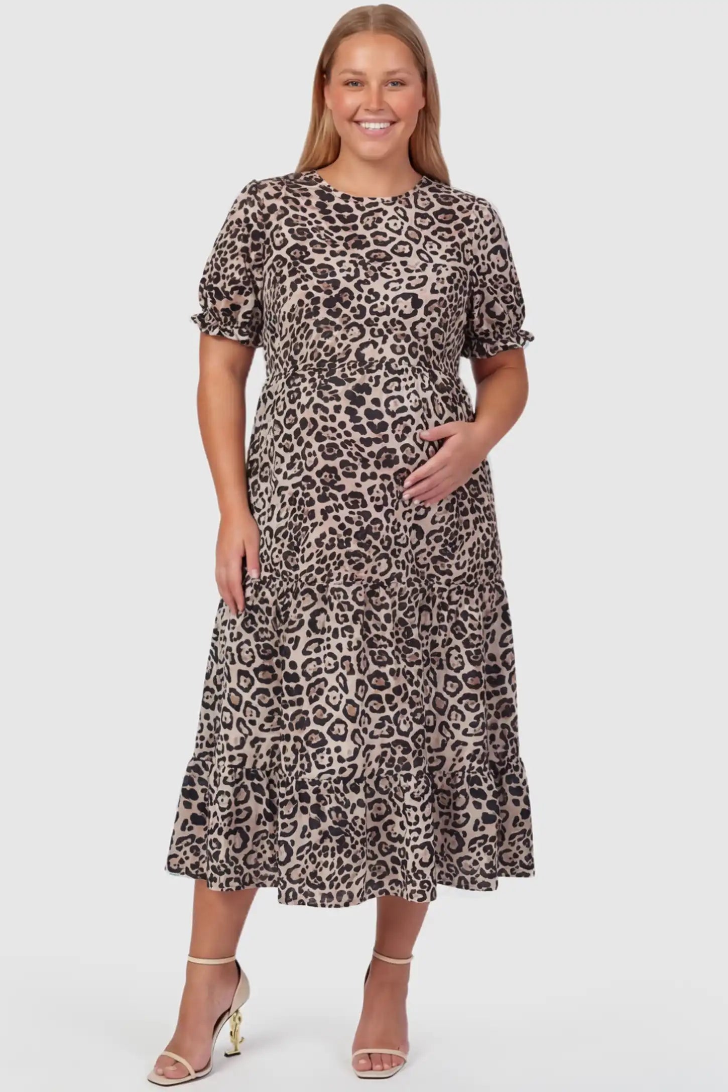 Printed Short Sleeve Tiered Maternity Midi Dress Printed Short Sleeve Tiered Maternity Midi Dress in leopard print featuring round neck, tiered A-line skirt on a plus size pregnant model, front view.