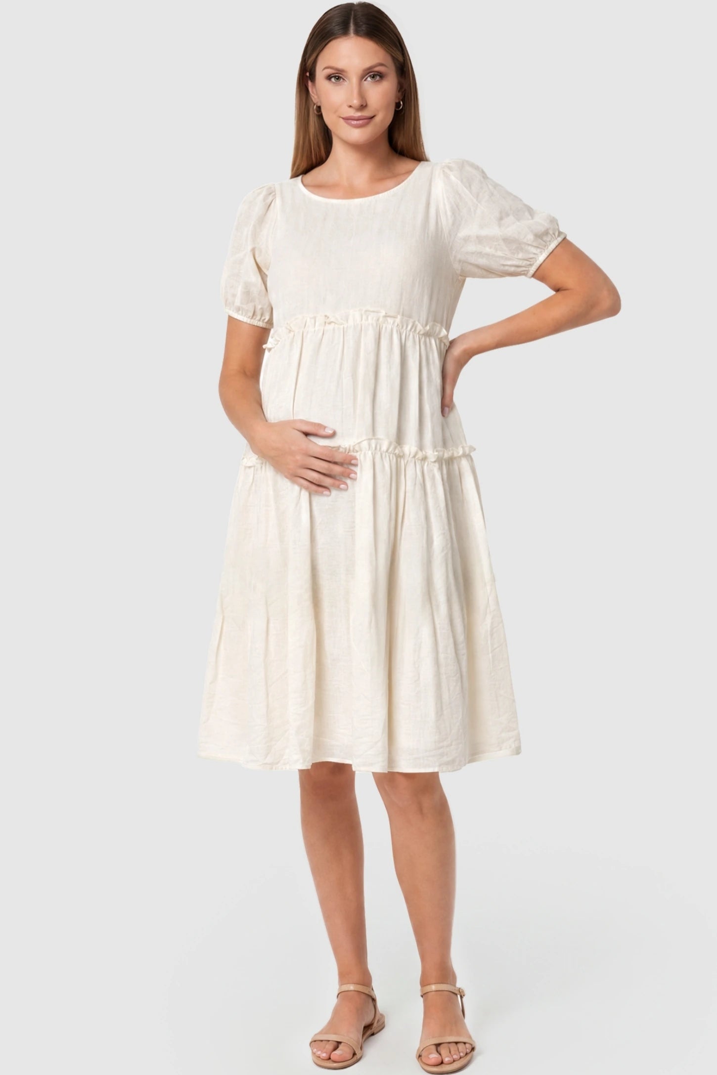 Puff Sleeve Tiered Midi Maternity Dress Puff Sleeve Tiered Midi Maternity Dress in Off-White featuring ruffled tiered skirt on a pregnant model, front view.