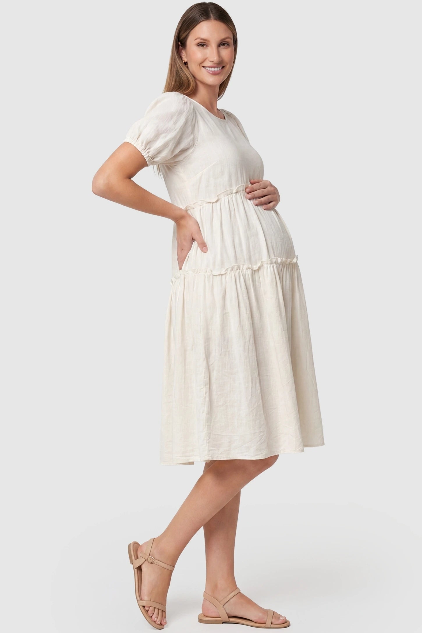 Puff Sleeve Tiered Midi Maternity Dress Puff Sleeve Tiered Midi Maternity Dress in Off-White featuring ruffled tiered skirt on a pregnant model, side view.